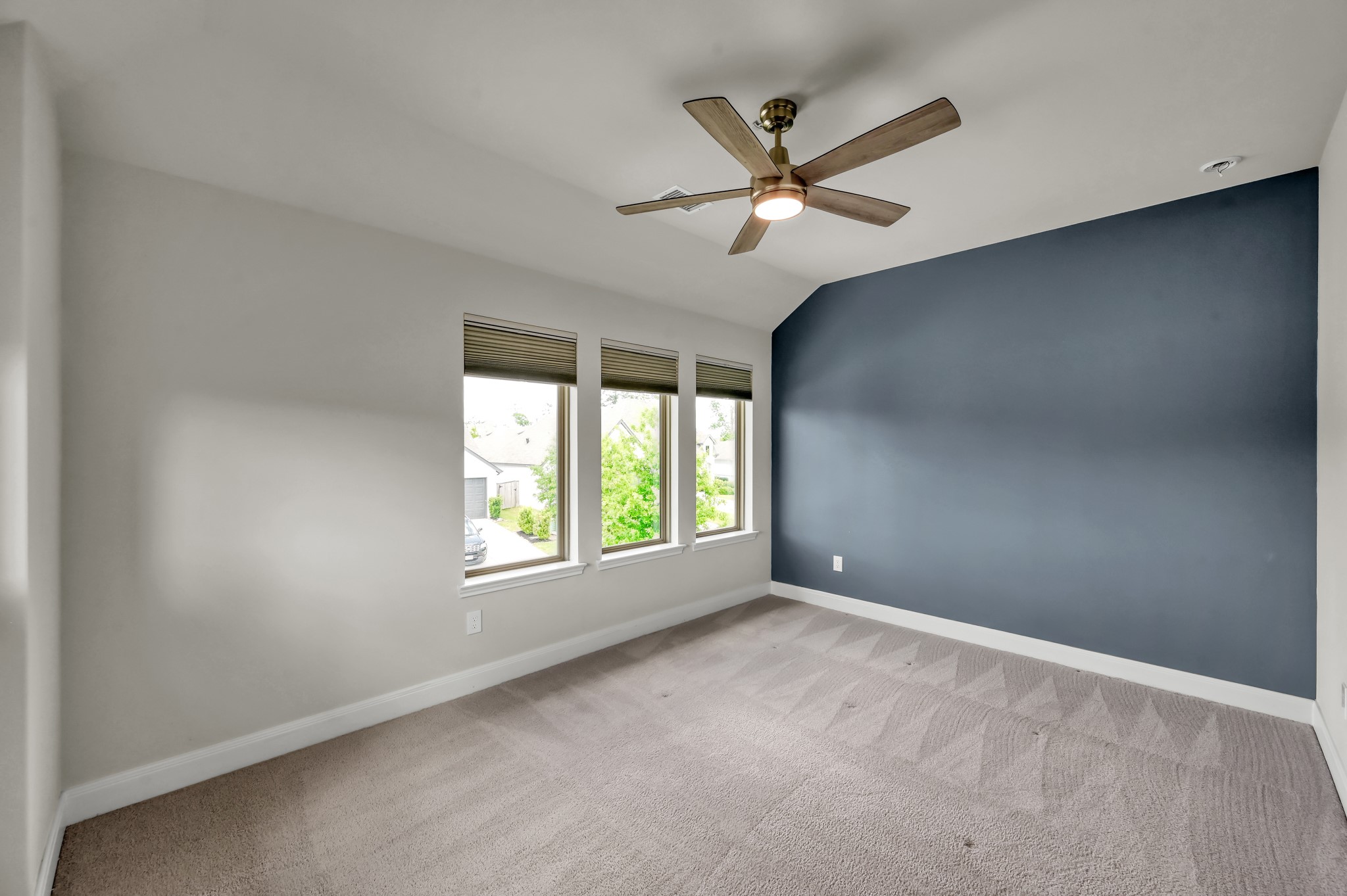 Bright secondary bedroom with clean carpeting, modern ceiling fan, and a stylish accent wall.