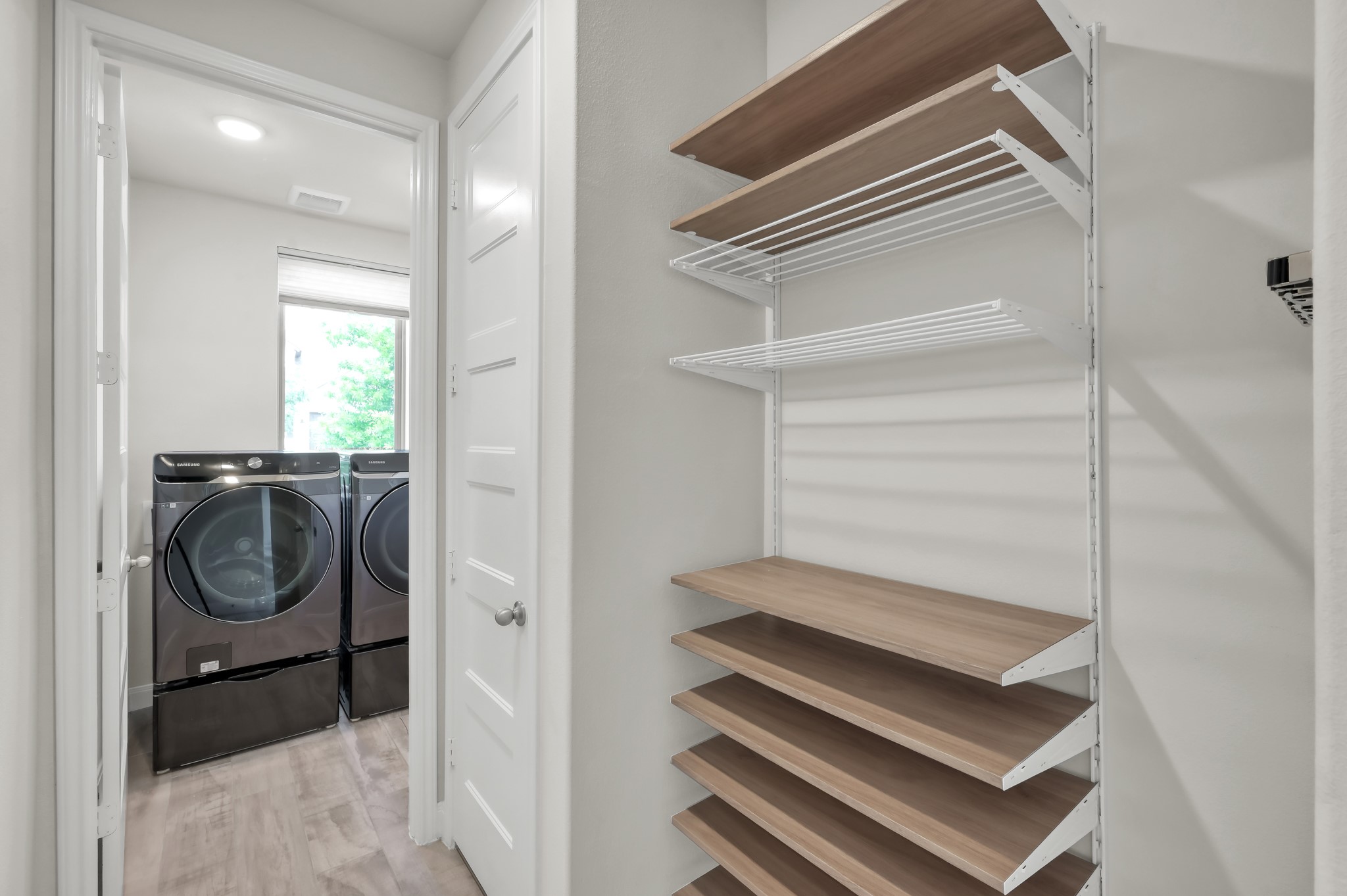 Clean, modern storage nook with adjustable shelving beside a bright laundry roomsimple and functional.