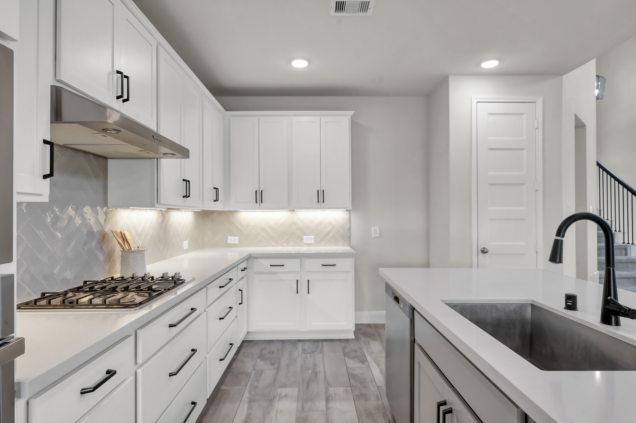 Bright kitchen with gas cooktop, sleek cabinetry, and stylish tile backsplash.