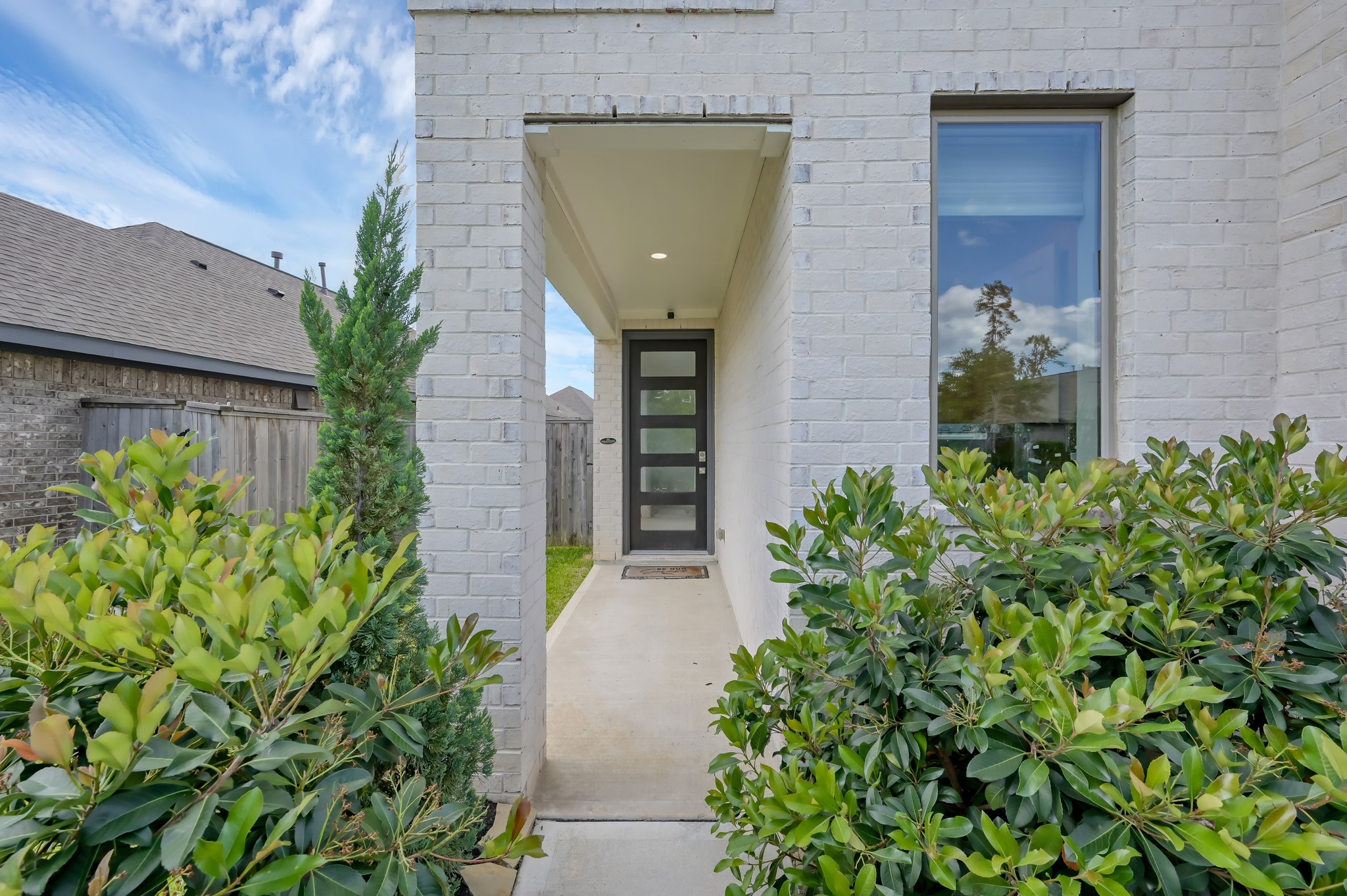 Inviting covered entry with modern front door and lush landscaping for added privacy.