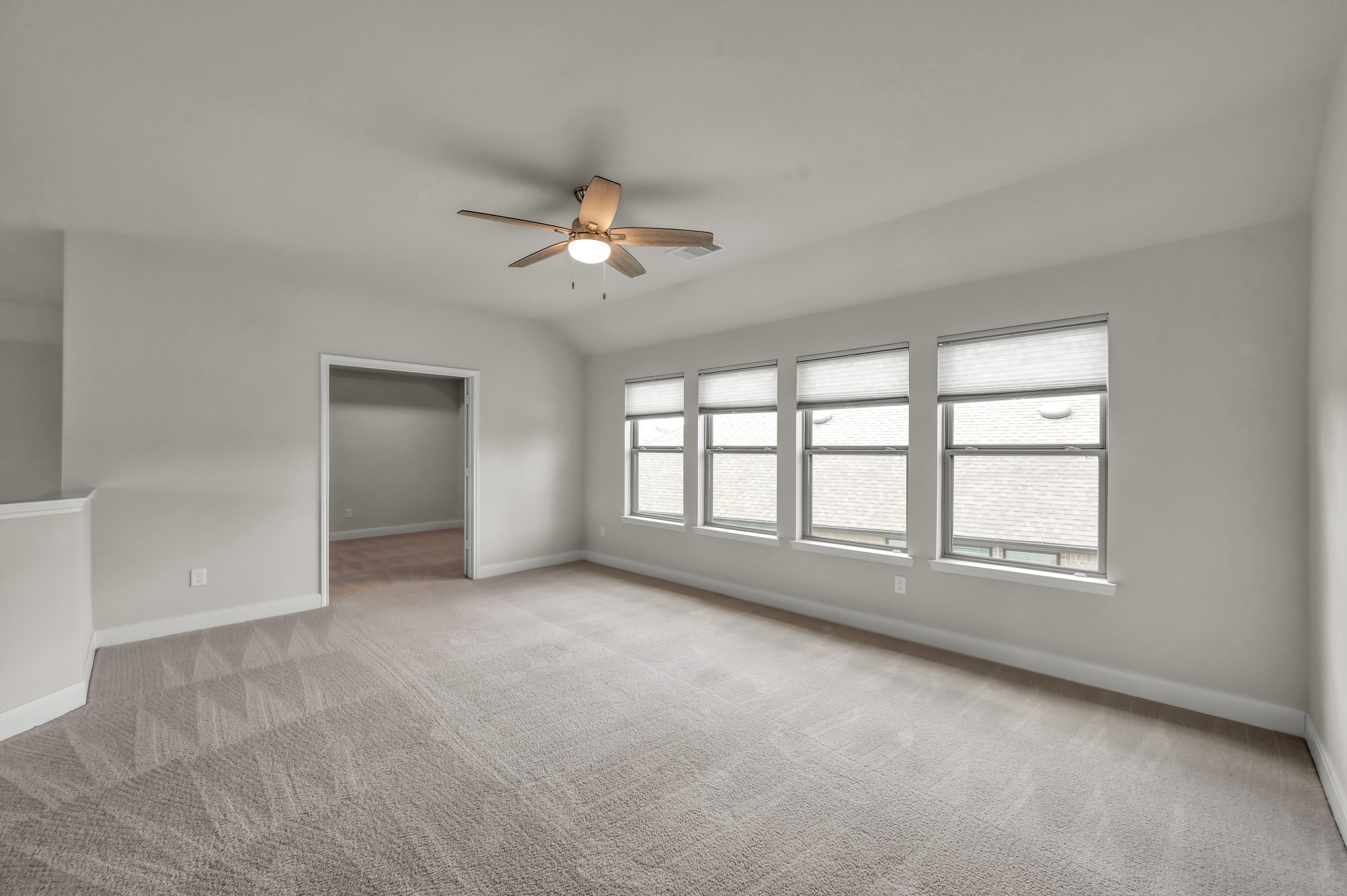 Spacious, bright game room with soft carpeting, multiple windows, and a clean, versatile layout.