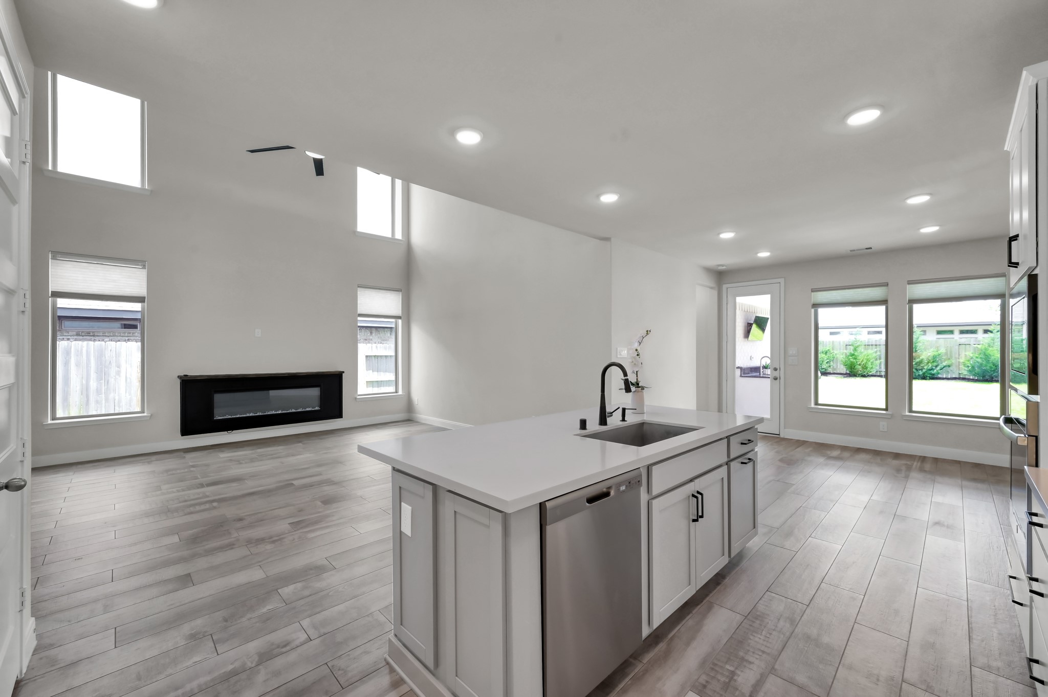 Kitchen overlooks spacious living area with abundant natural light and backyard views.