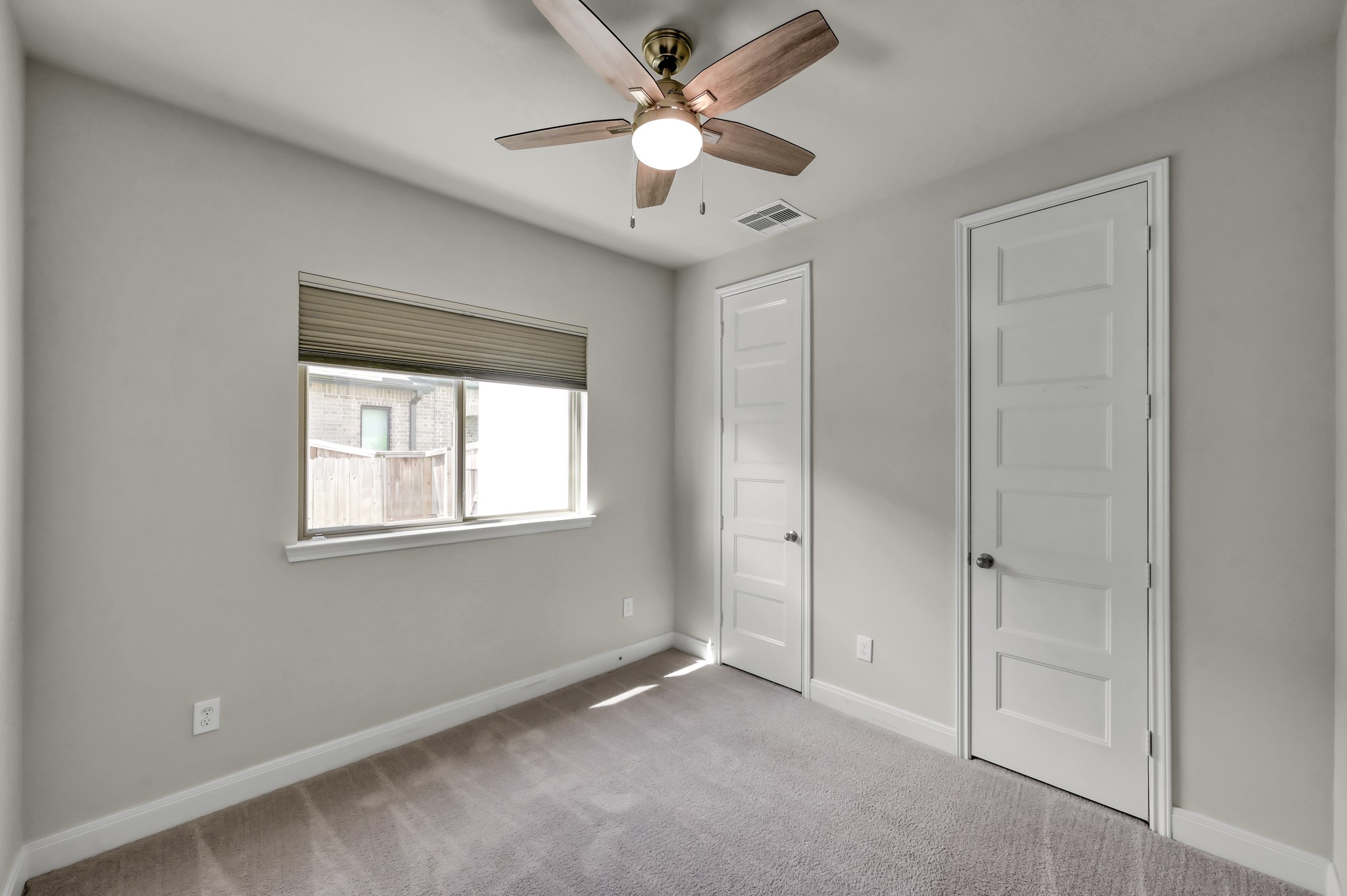 Secondary bedroom down with plush carpeting, ceiling fan, and ample closet space.