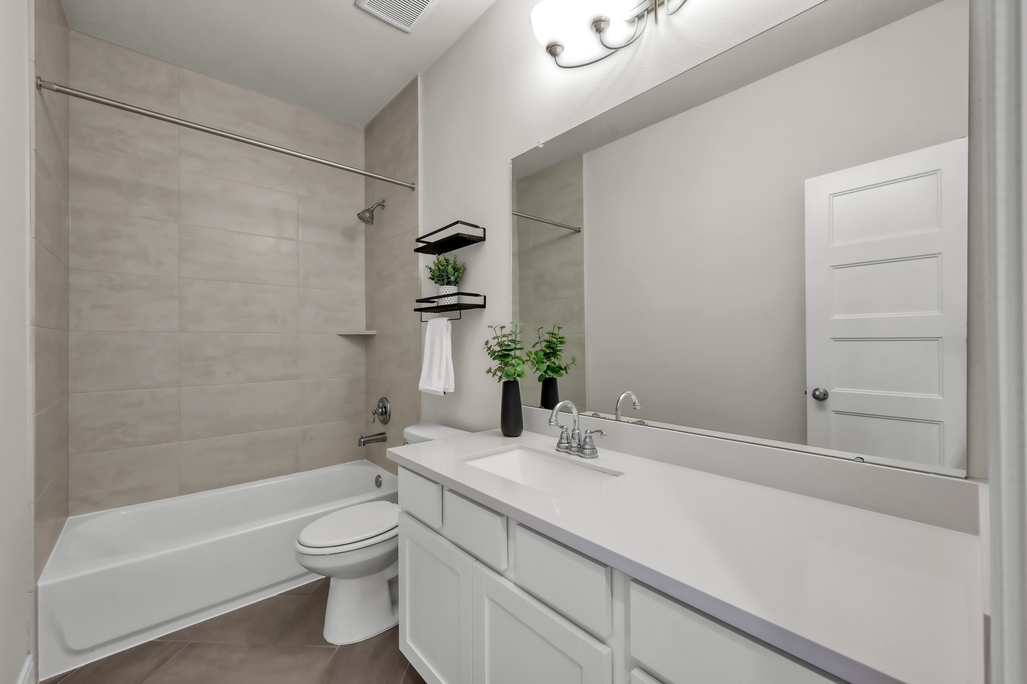 Clean, modern bathroom featuring a sleek vanity, large mirror, and tiled shower/tub combo for a fresh, move-in-ready feel.