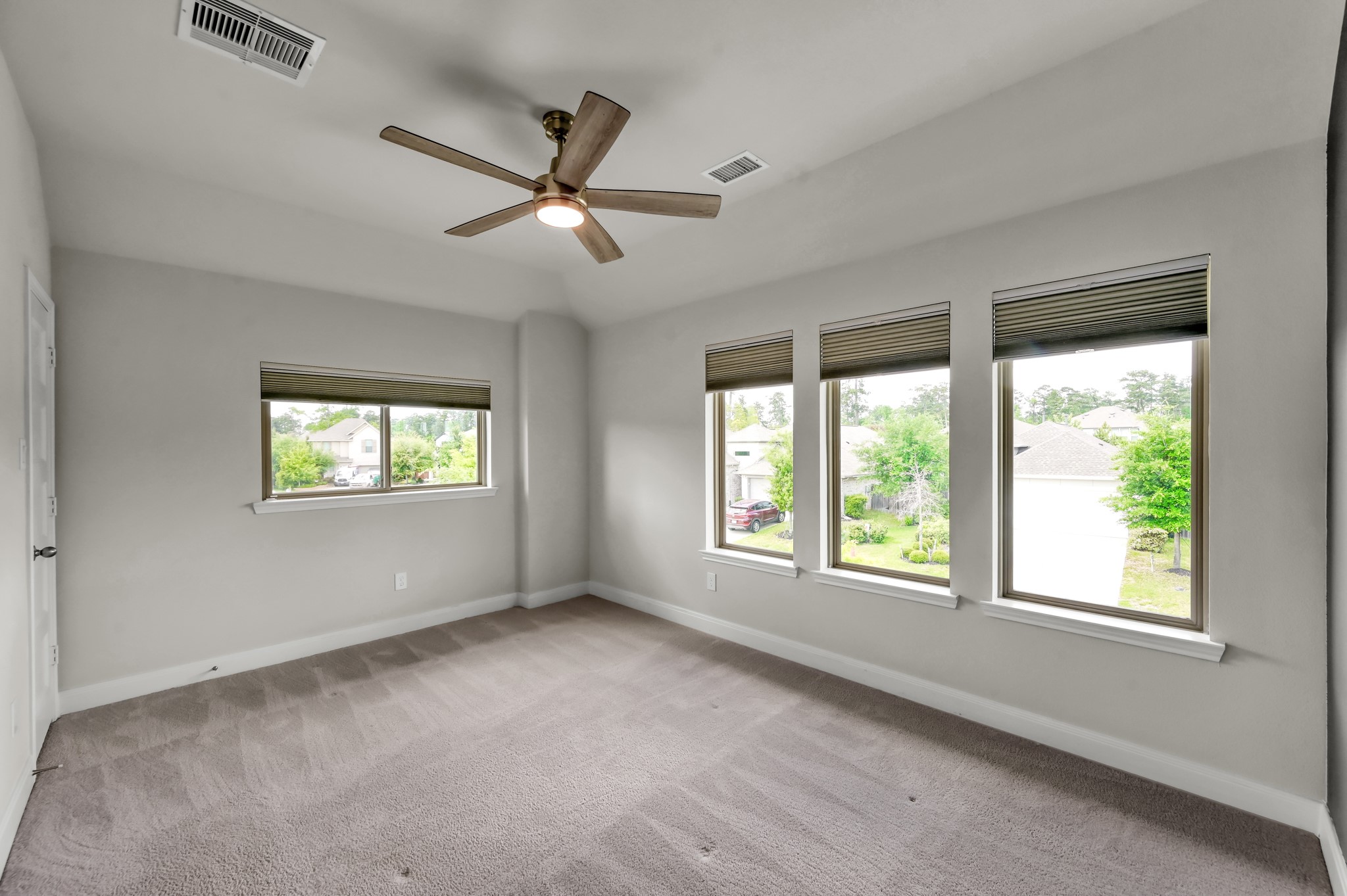 Additional view of secondary bedroom with plenty of natural light from the triple windows adds an inviting feel.