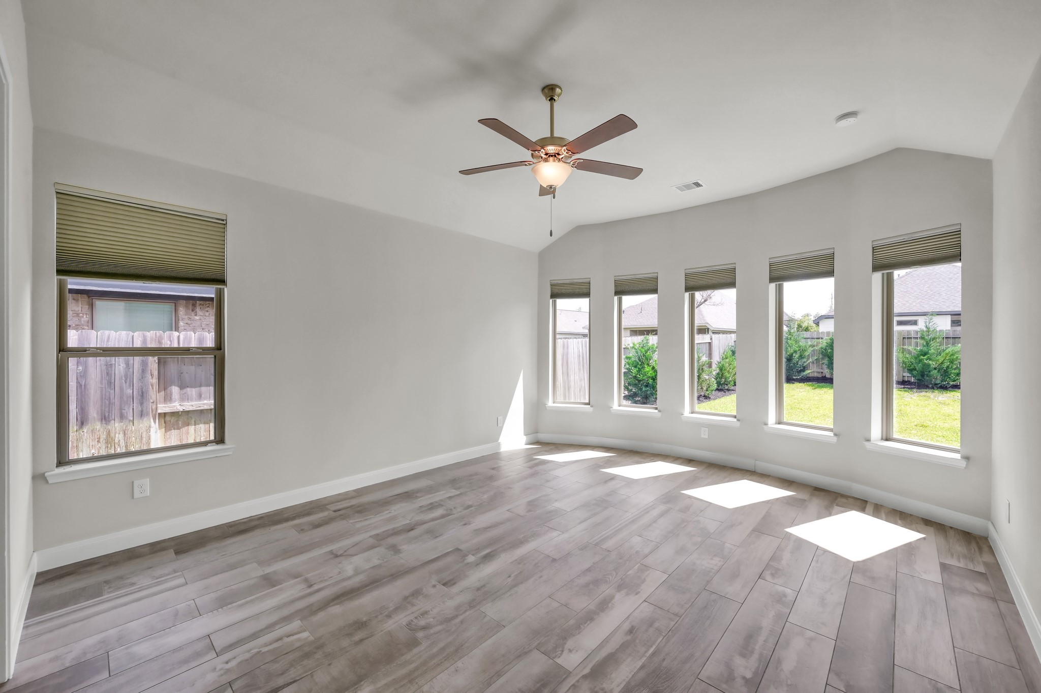 Spacious primary suite with wall of windows, abundant natural light, and serene backyard views.