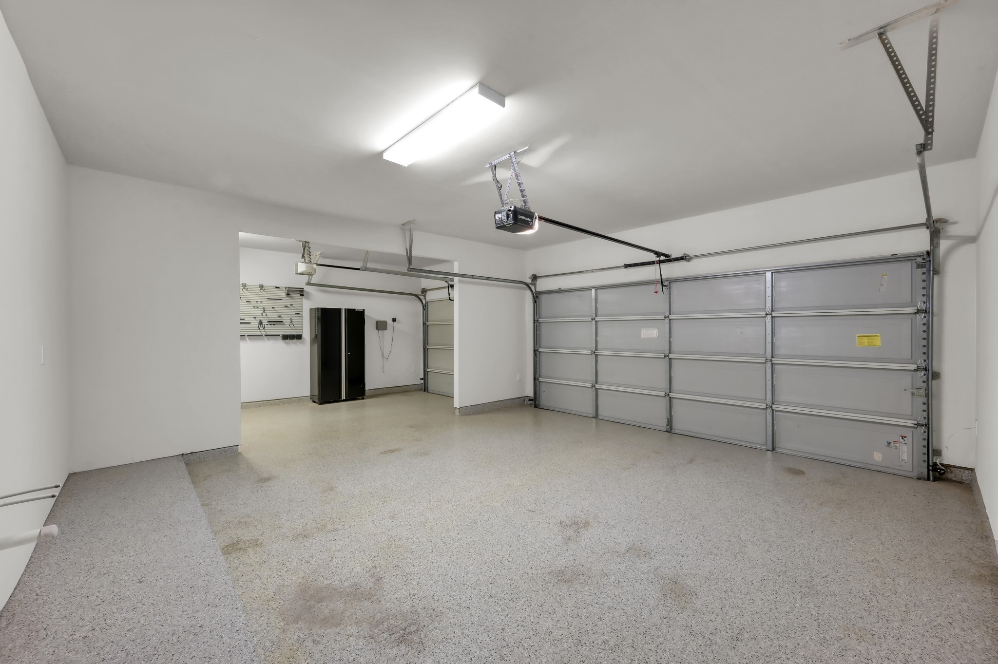 Oversized 3-car garage featuring durable epoxy flooring  perfect for storage or hobbies.