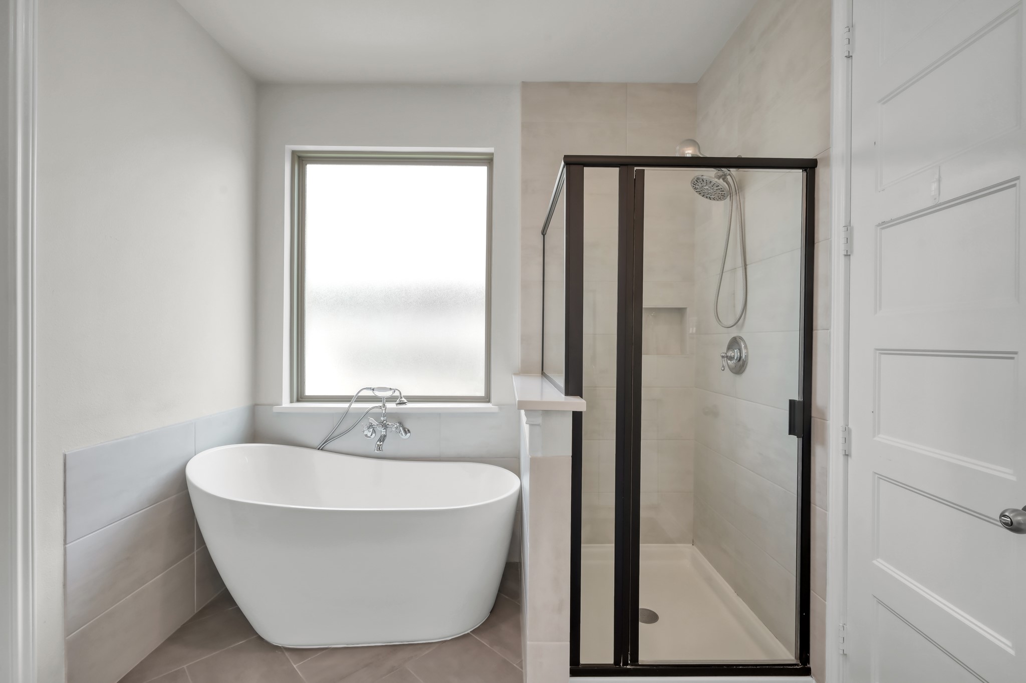 Spa-like primary bath with freestanding soaking tub and separate glass-enclosed shower.