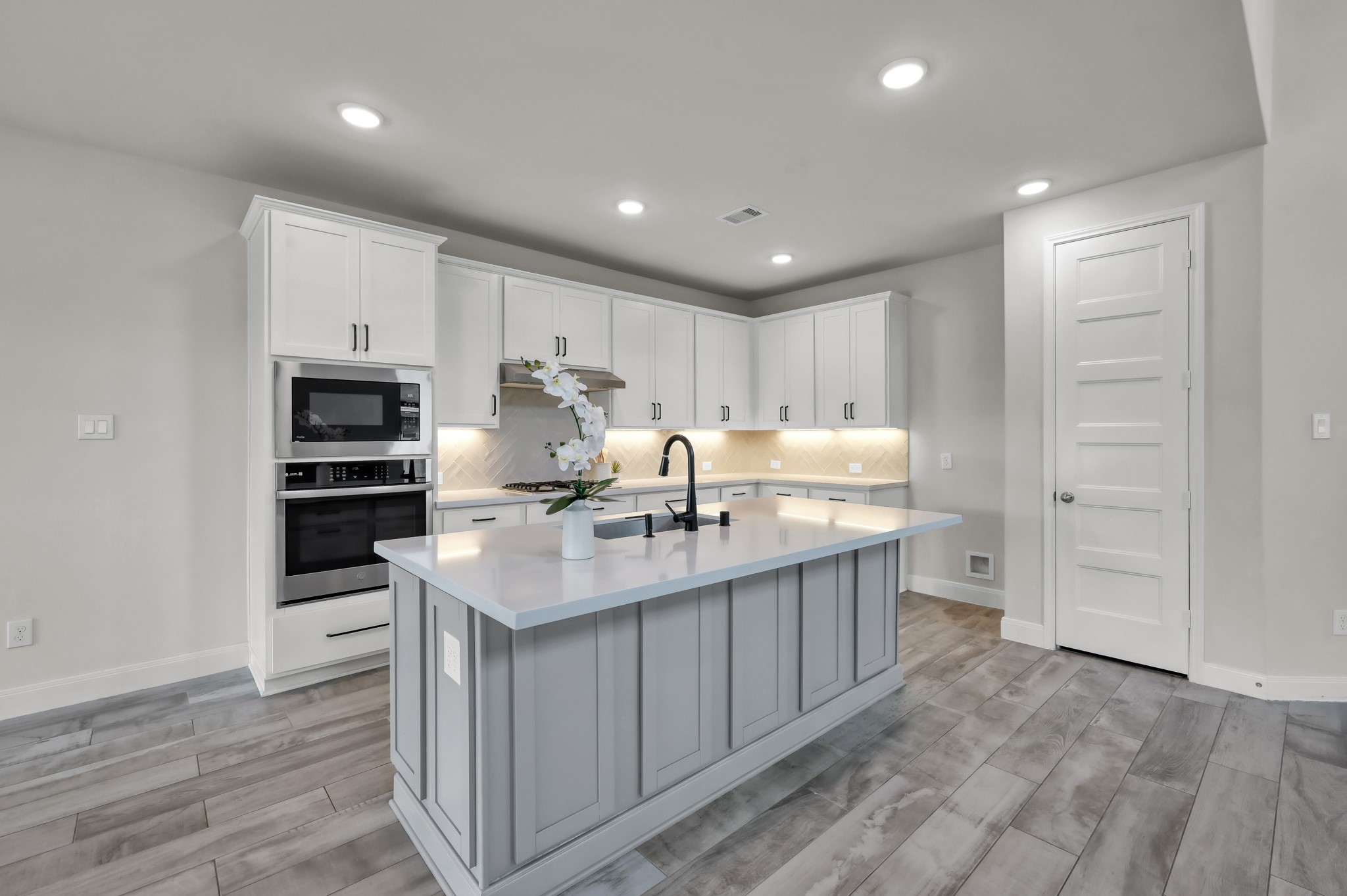 Chefs kitchen with large island, quartz countertops, stainless steel appliances, and abundant cabinetry.