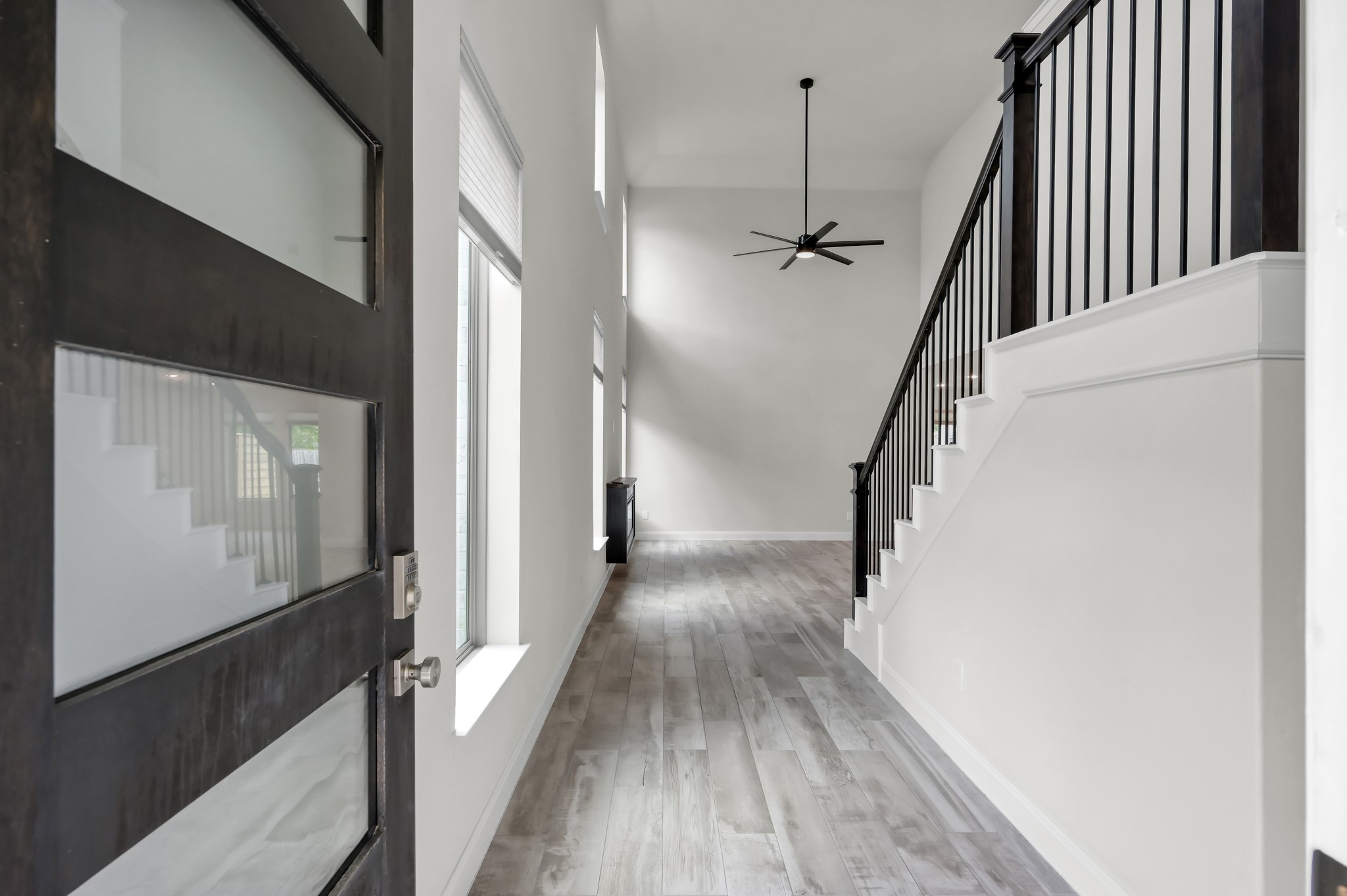 Grand entry with soaring ceilings, wood-look tile flooring, and a striking staircase.