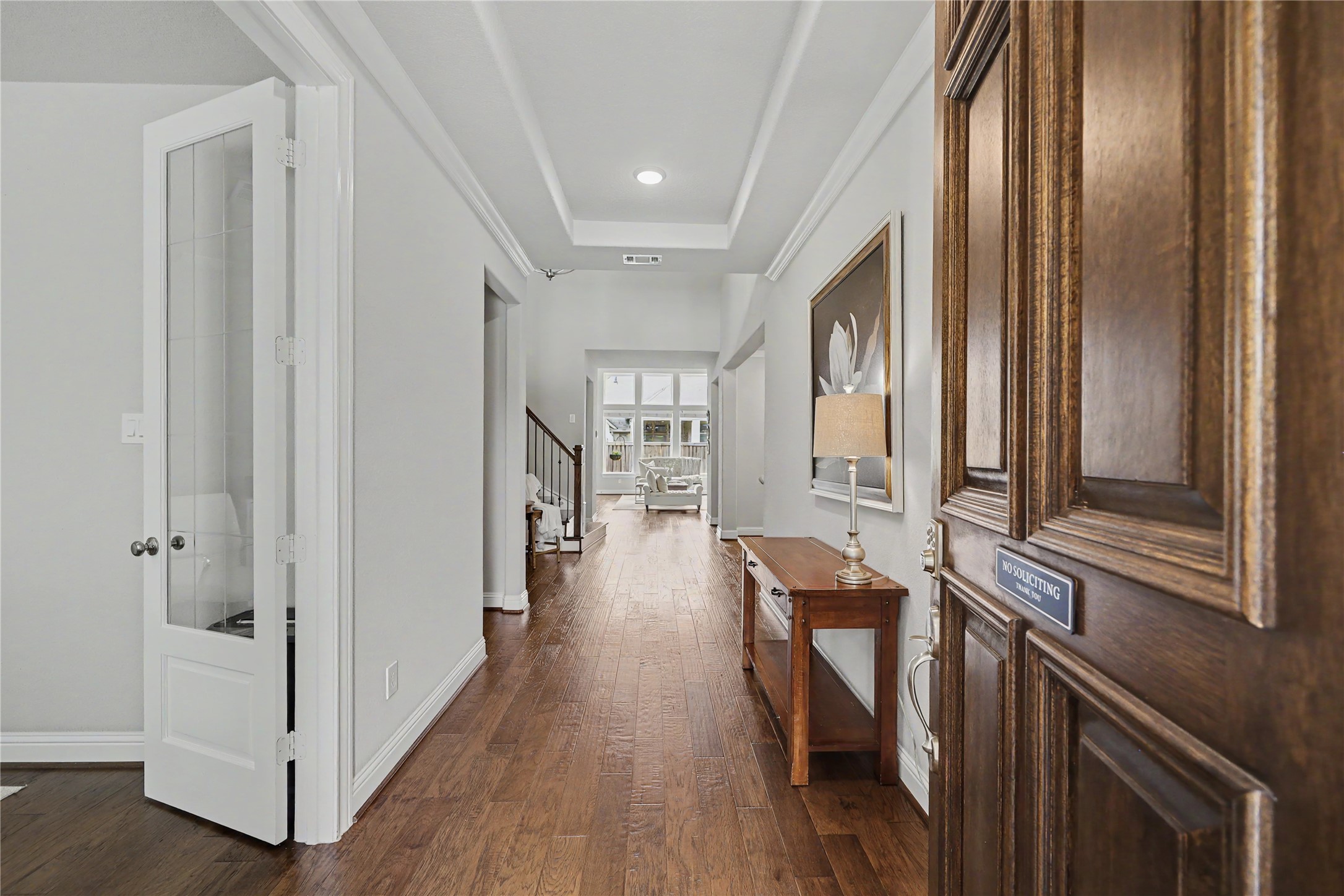 Entry foyer with wood flooring, decorative molding, and views into the home.