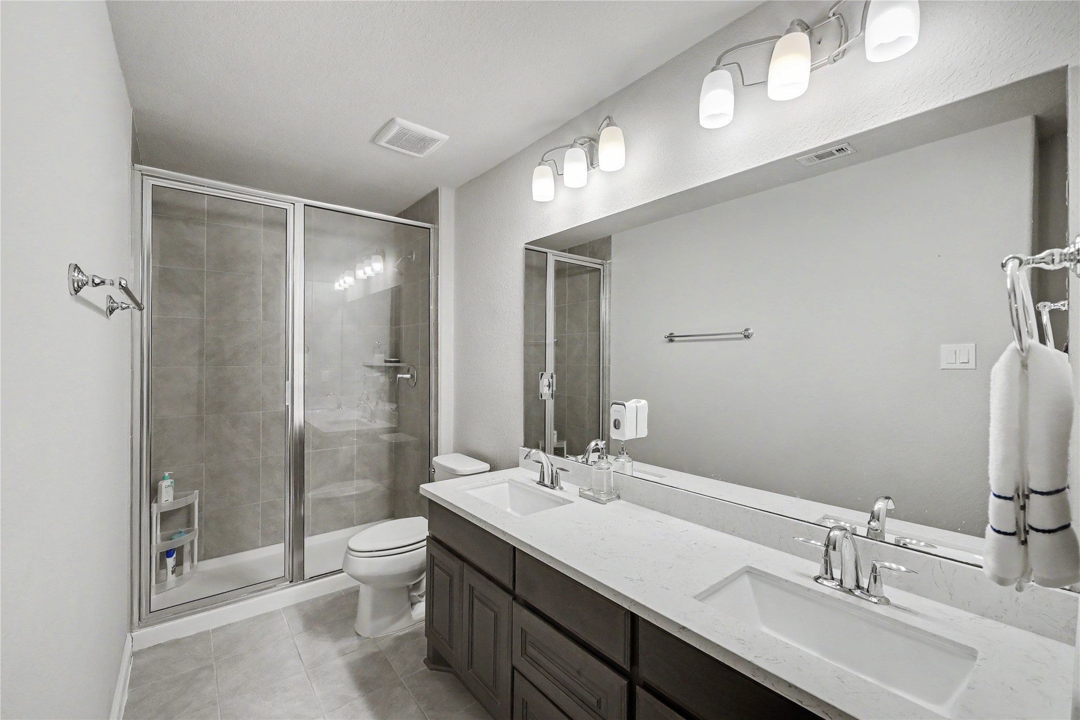 Secondary bathroom featuring a spacious vanity, large mirror, and tub/shower combination.