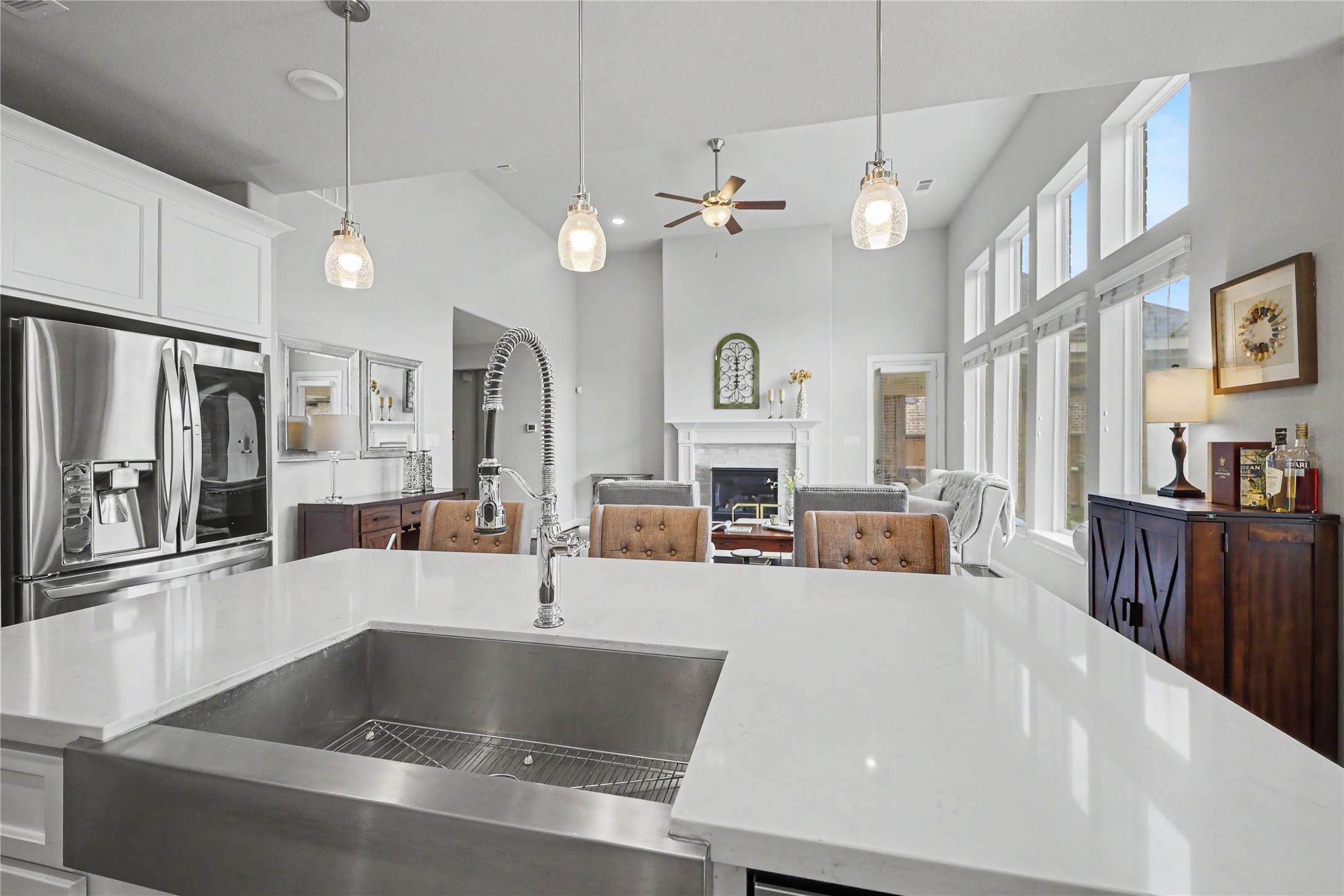 Great room view with soaring ceilings, tall windows, and fireplace from kitchen island.