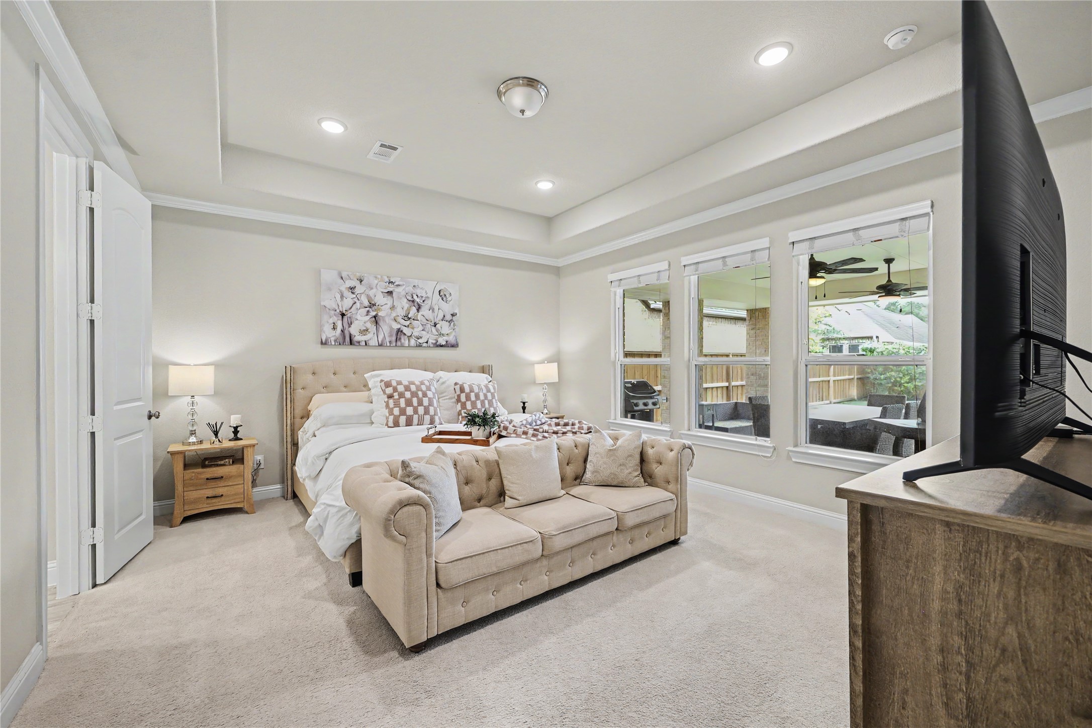 First-floor primary suite with tray ceiling, crown molding, and generous natural light.