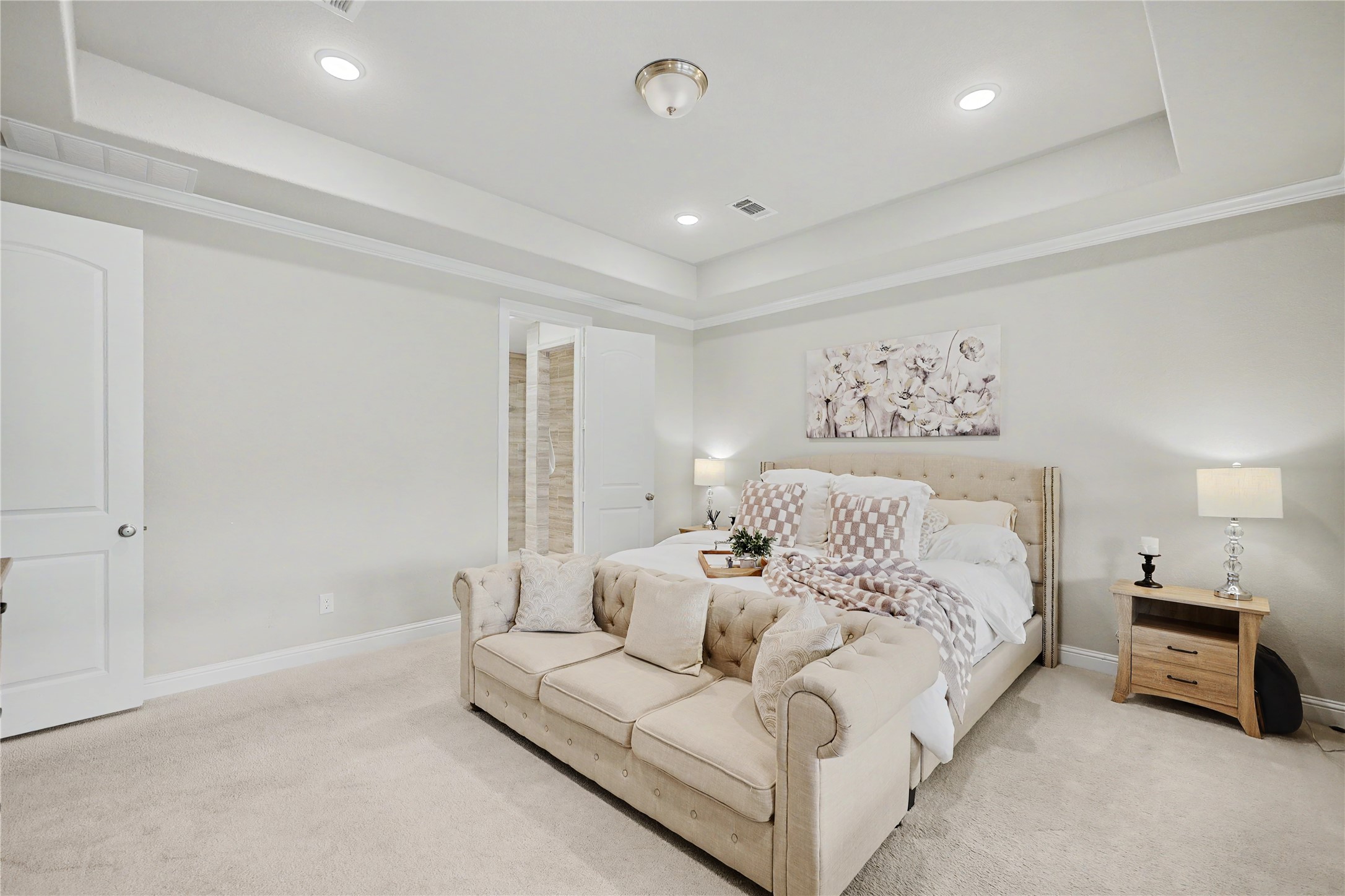 Additional view of the primary suite featuring a tray ceiling and neutral finishes.