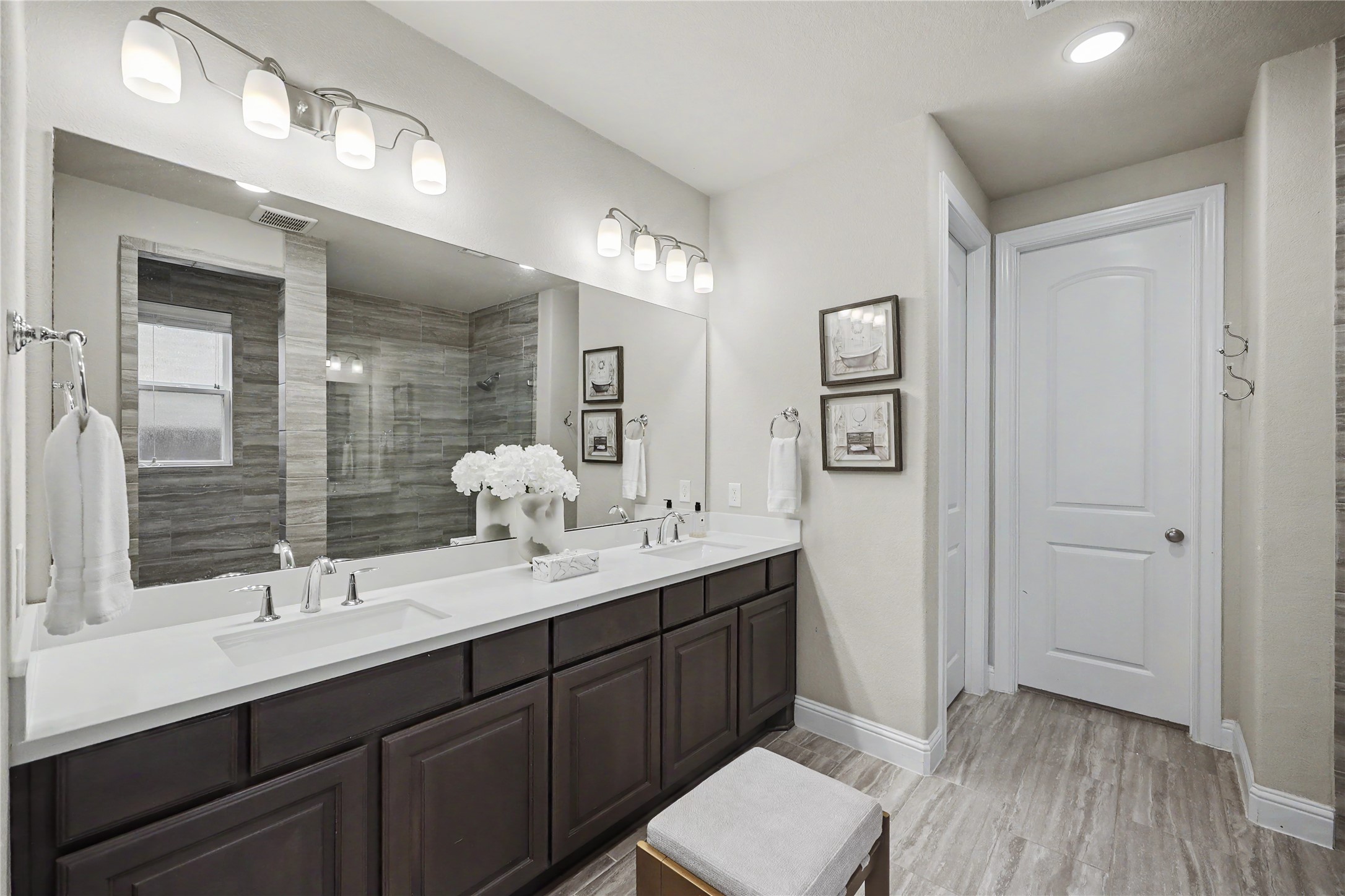 Additional view of the primary bathroom with extended dual-sink vanity and ample cabinetry.