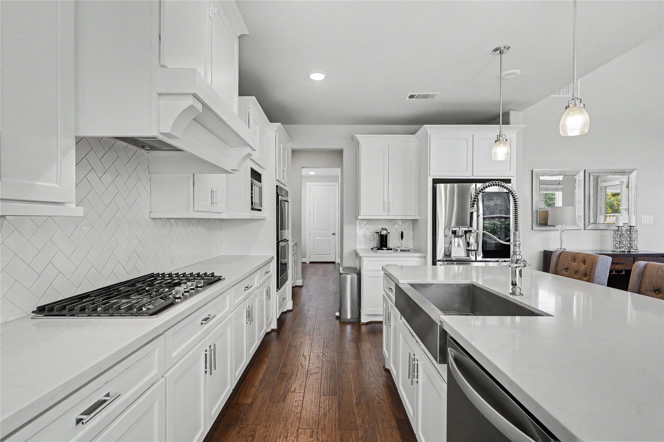 Kitchen featuring built-in appliances, white cabinetry, and island seating.