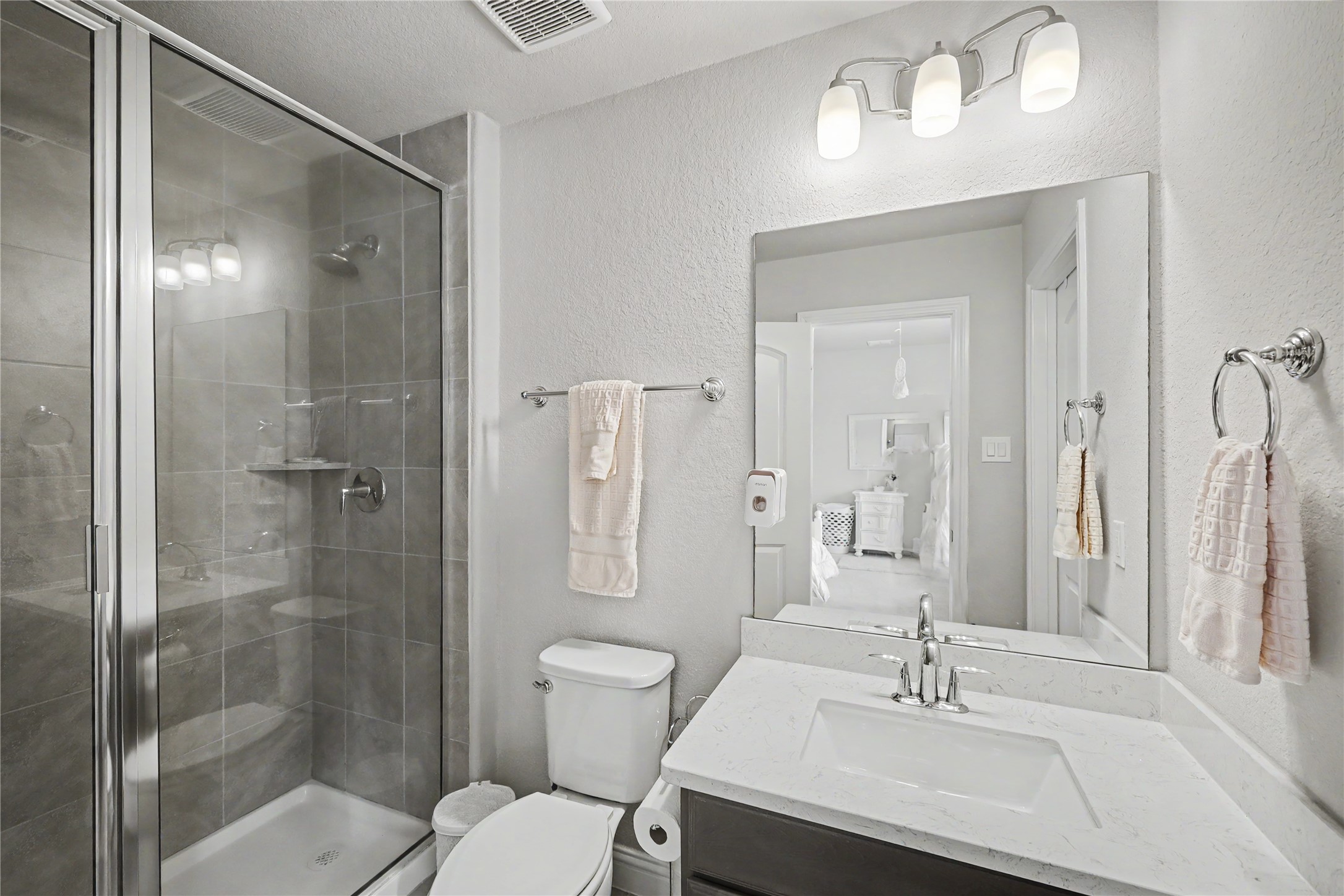 Secondary en-suite bathroom with vanity, framed mirror, and glass-enclosed shower.