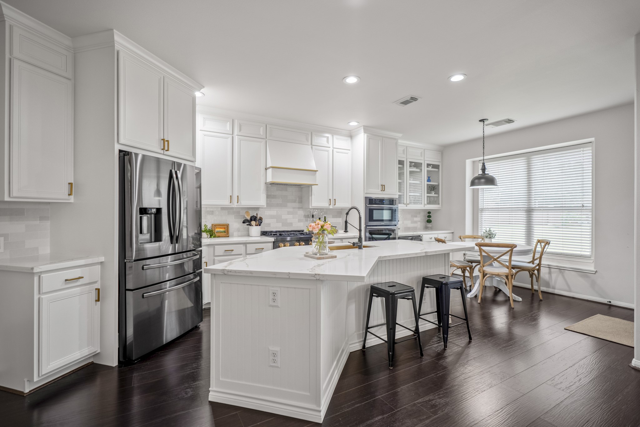 The kitchen is the true heart of the home, a light-filled, gourmet kitchen is a masterpiece featuring an expansive island with a breakfast bar overhang, beautifully wrapped in classic white beadboard and topped with luxurious quartz countertops.