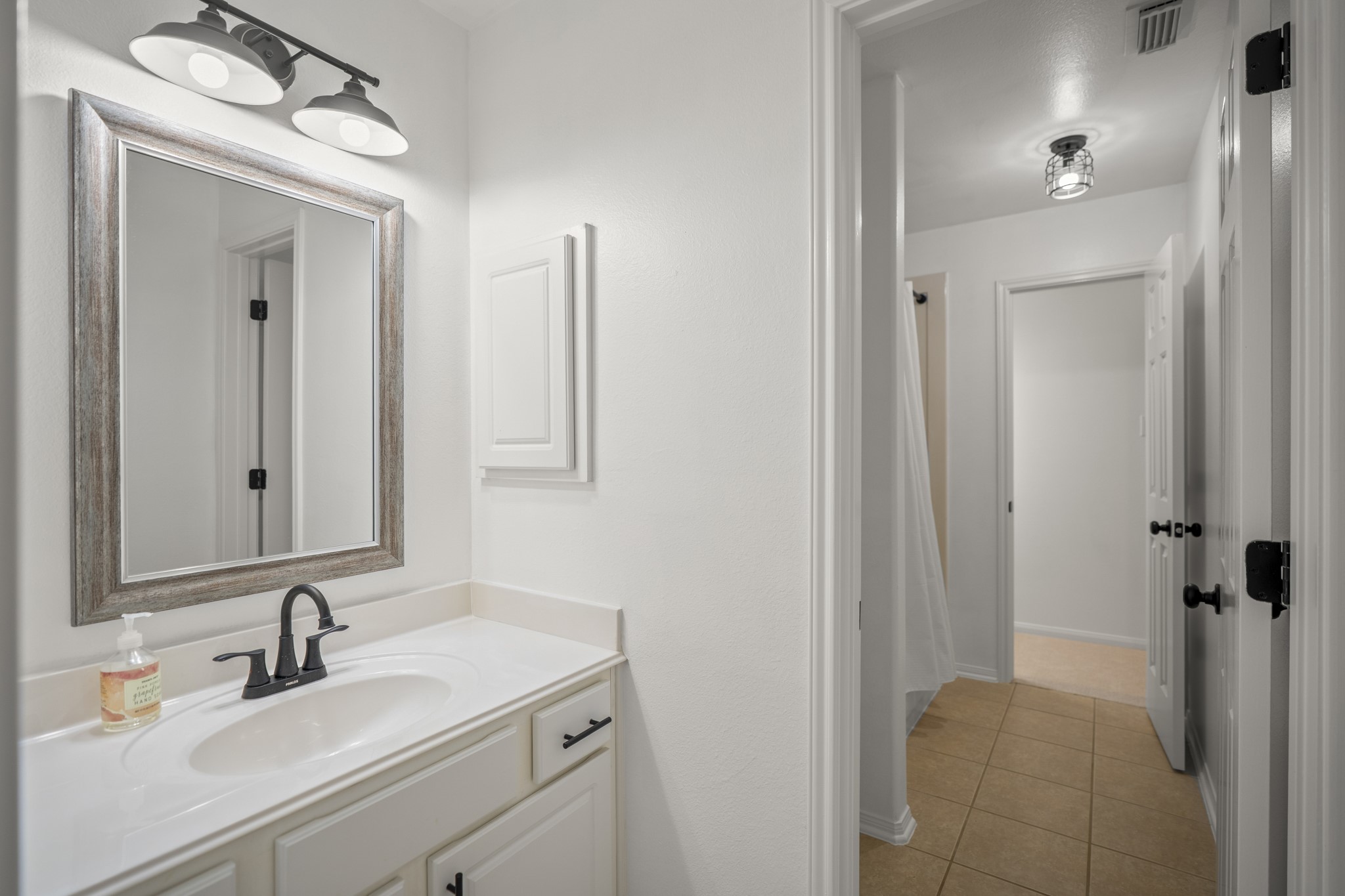 The upstairs shared bathroom has updated lighting, and a nice framed mirror, as well as plenty of storage and a tub / shower combo.