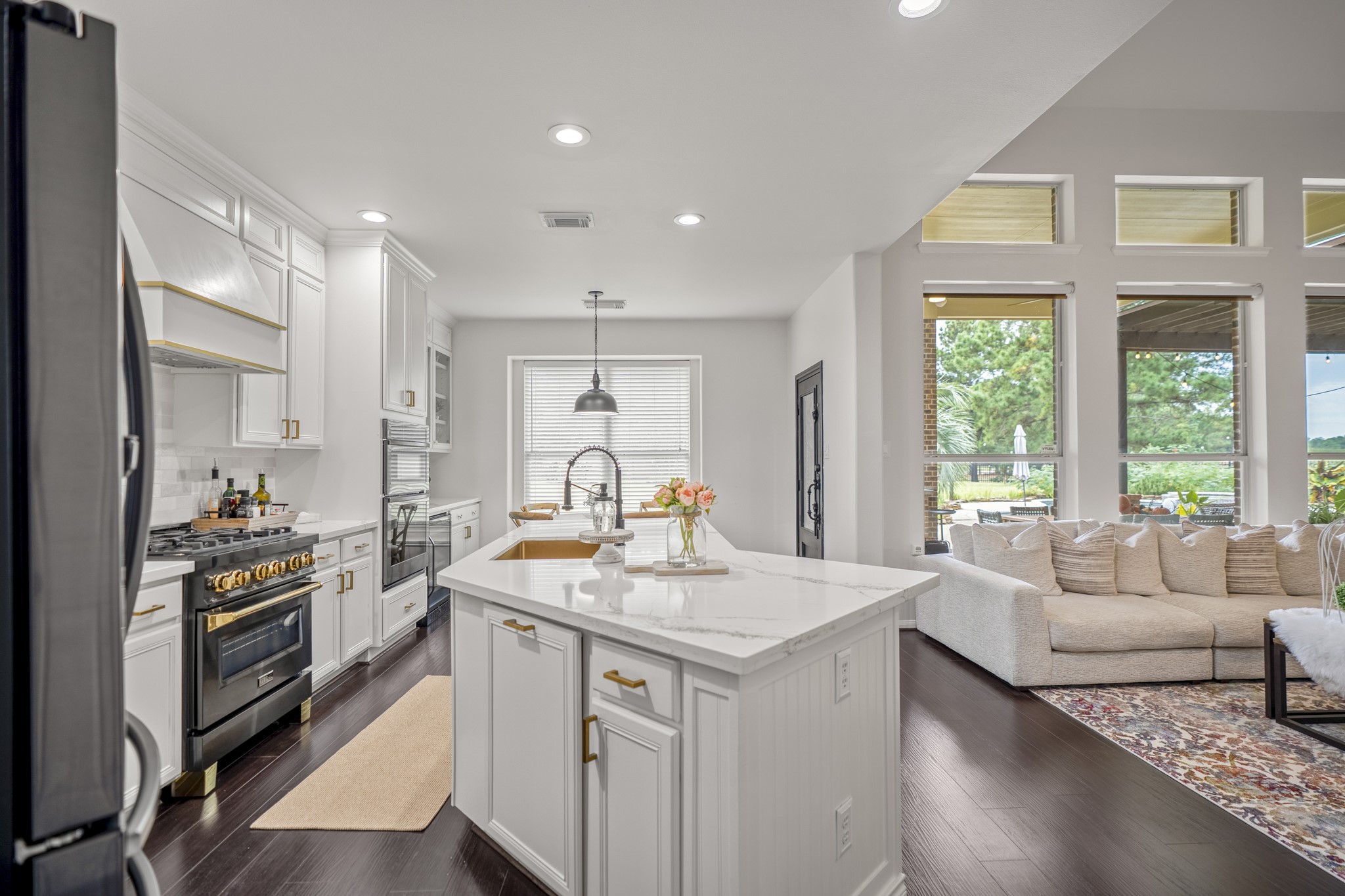 The gourmet kitchen offers high-end features; wall ovens, a built-in microwave, ZLINE four-burner gas range, designer hardware, gooseneck faucet, and custom vent hood trimming.