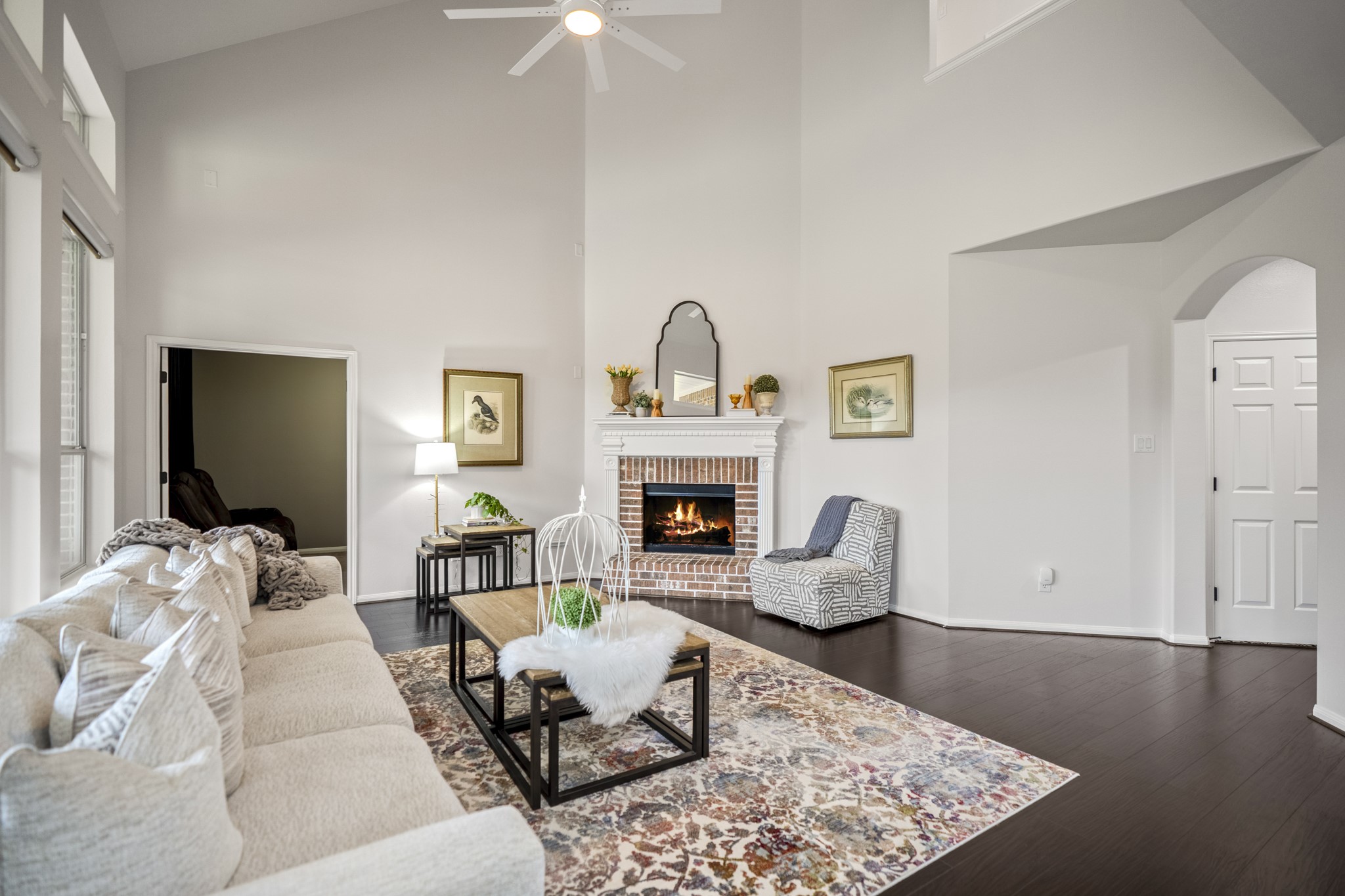 The central focus is a stunning brick-accented fireplace featuring a detailed white mantle, perfect for cozying up on cooler evenings and looking forward to being decorated for the holidays.