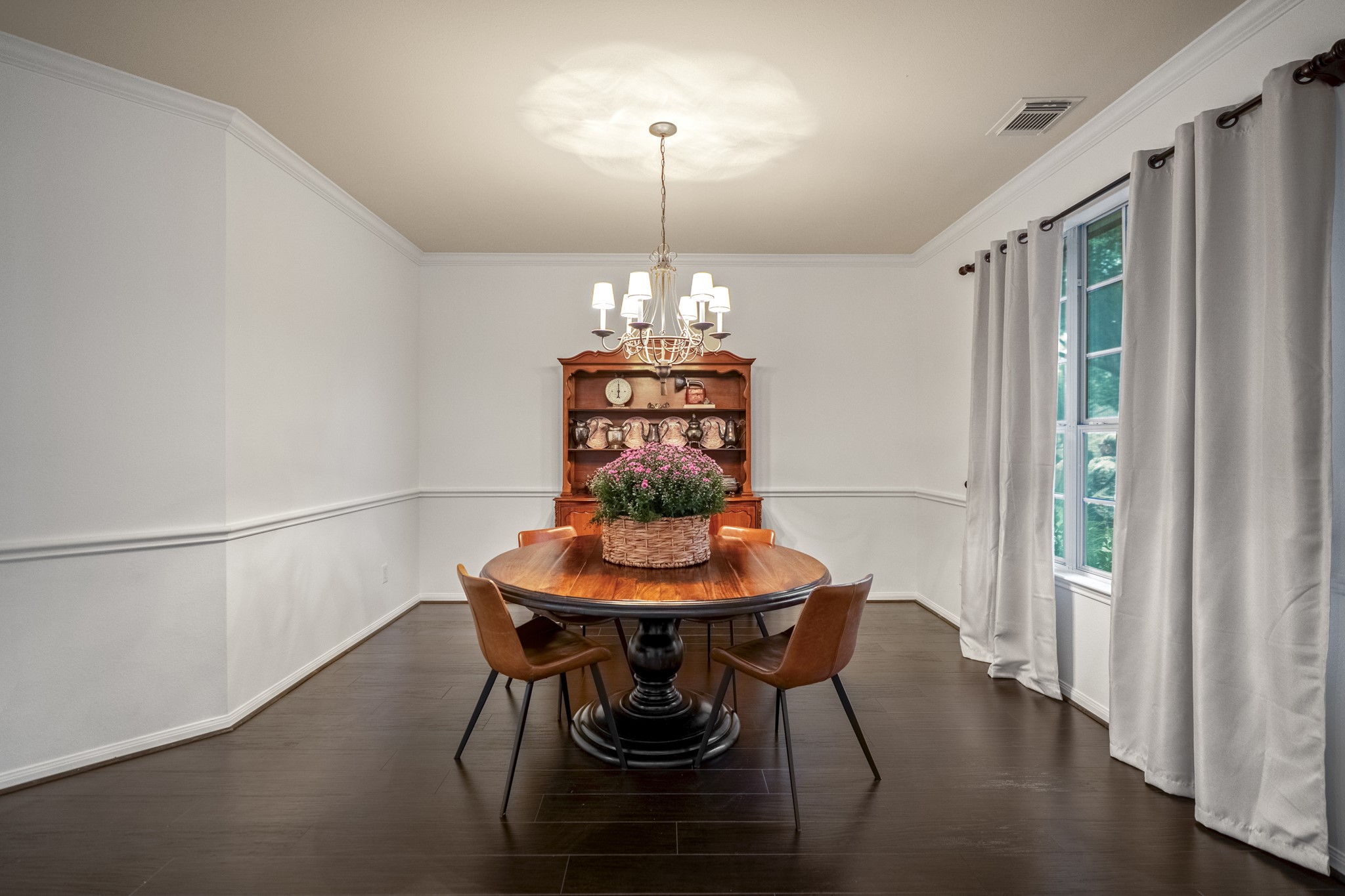 The formal dining room offers an airy atmosphere, while the rich, dark wood look flooring offers a striking, high-end contrast to the crisp white trim and neutral walls.