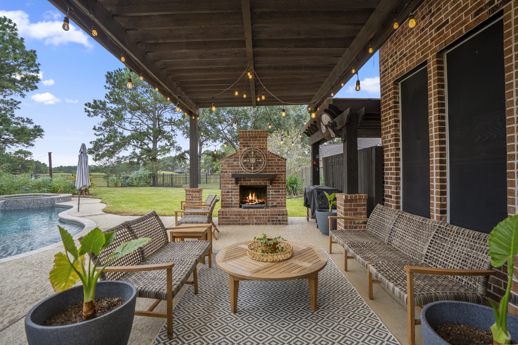 Spend relaxing evenings under the pergola accented by festive bistro lighting, which anchors a cozy freestanding brick fireplace, while taking in spectacular views of the golf course, sparkling in-ground pool, spa and sprawling, private green lawn framed by mature trees.
