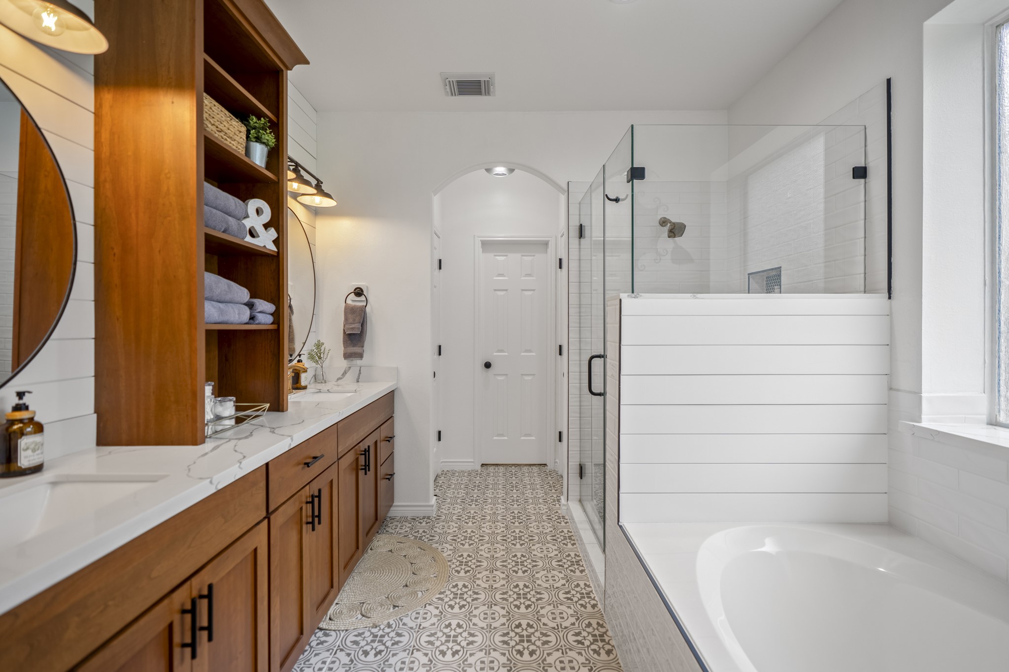 Beautiful updated en-suite bathroom features updated flooring, cabinetry and lighting, soaking tub, and glass enclosed shower.