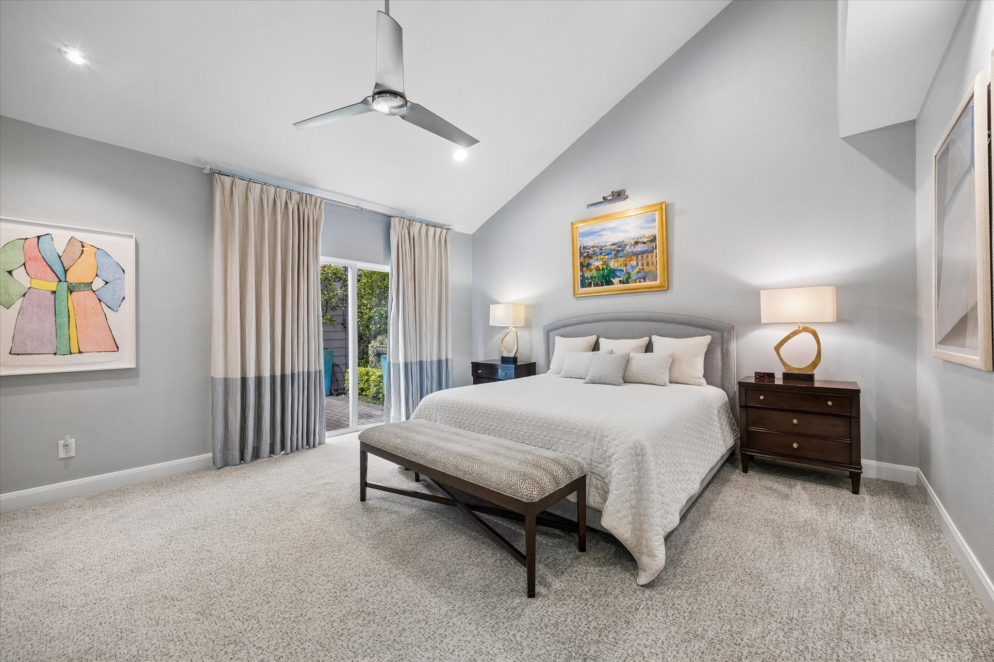 PRIMARY BEDROOM: Spacious primary retreat features vaulted ceilings, plush custom carpeting, custom window treatments, 2 walk-in closets with built-ins, a sleek ceiling fan and sliding glass doors overlooking the atrium space.