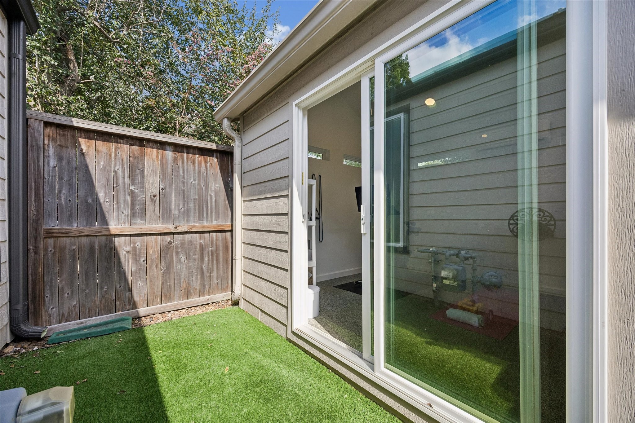 Private outdoor area features low-maintenance turf installed in 2022, providing a versatile extension of the custom-built fitness studio.