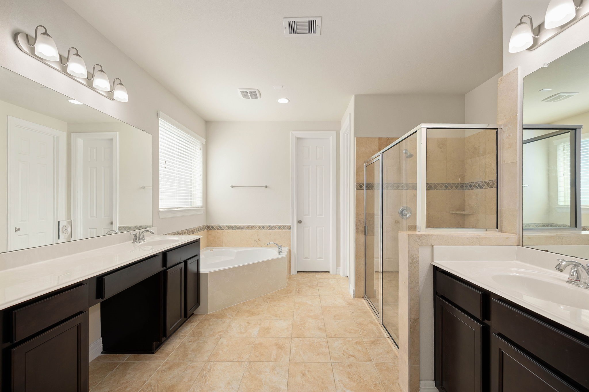 Spacious en-suite bath featuring dual vanities with generous counter space, a soaking tub, separate glass-
enclosed shower, huge walk-in closet, linen closet, and plenty of cabinetry for storage.
