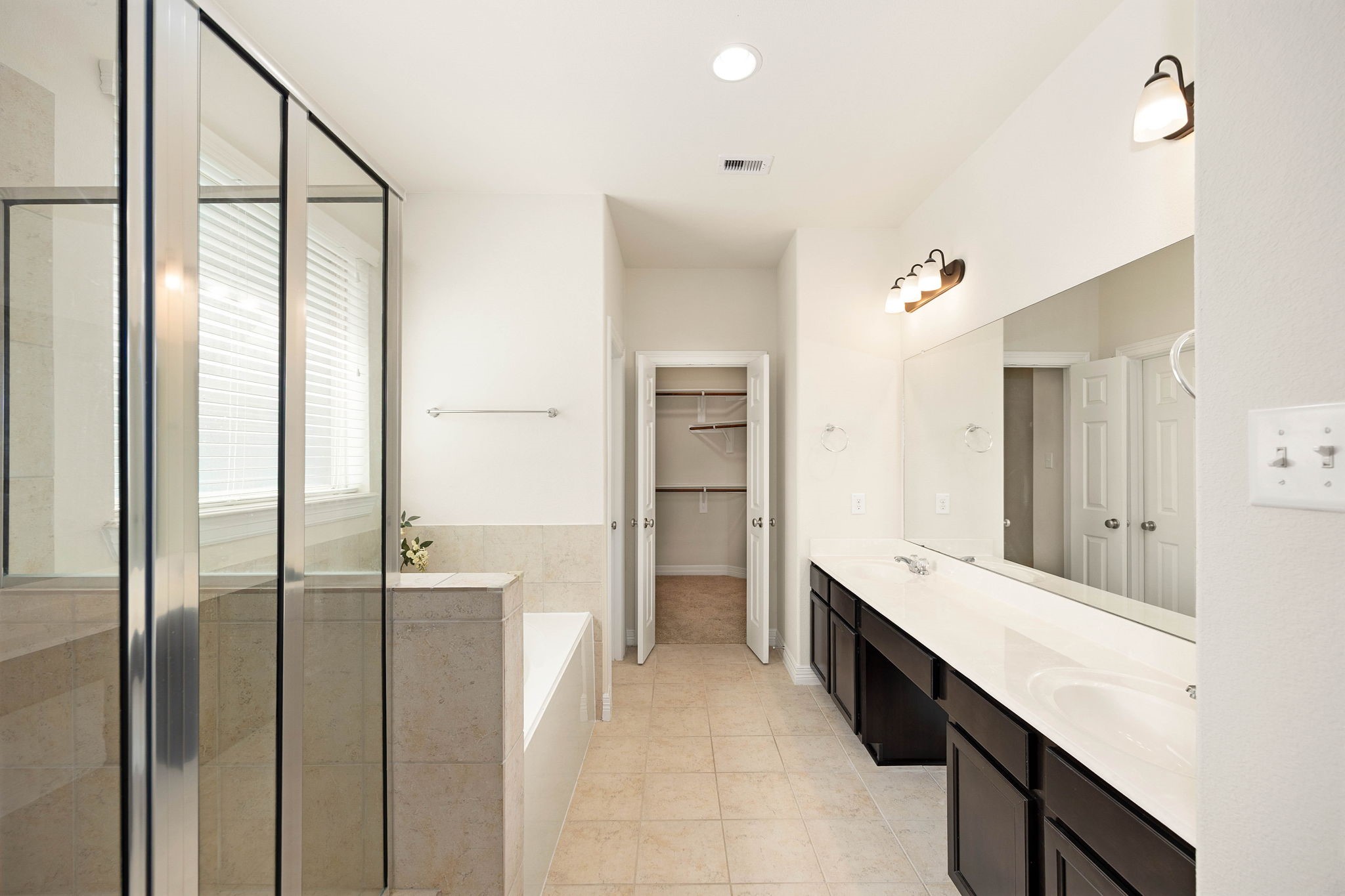 Private en-suite bath features a double sink vanity with abundant counter and cabinet space, separate shower, soaking tub, and walk-in closet.