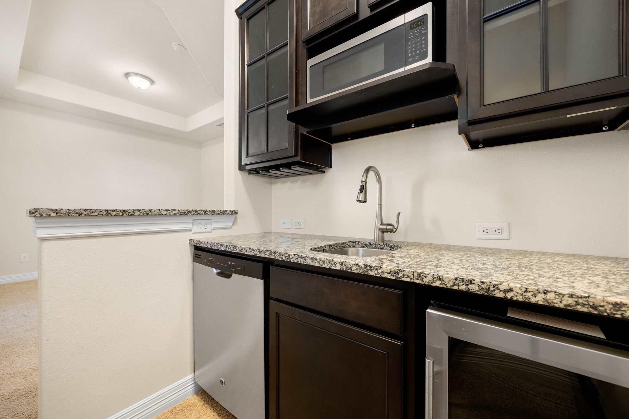 The private living space in this second floor primary suite also features a convenient kitchenette with granite countertops, sink, cabinets, dishwasher, and wine fridge!