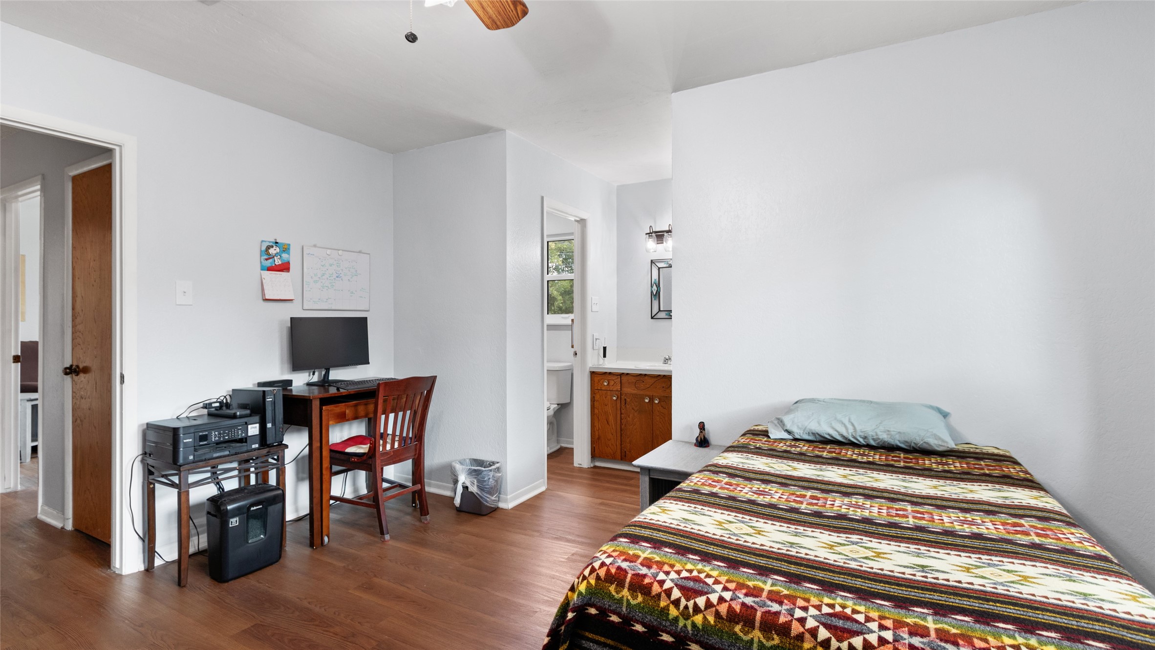 Alternate view highlights the bedrooms generous layout, wood-look flooring, ample wall space, and direct access to the adjoining bath.