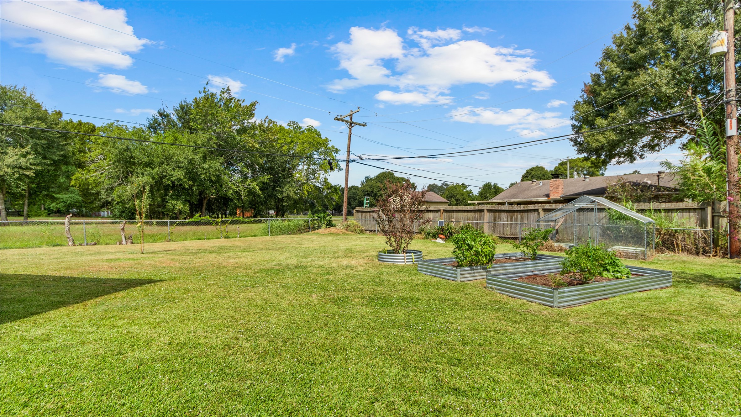 Expansive backyard offers plenty of open green space along with established raised garden beds and a greenhouseideal for gardening, outdoor activities, or creating your own backyard retreat.