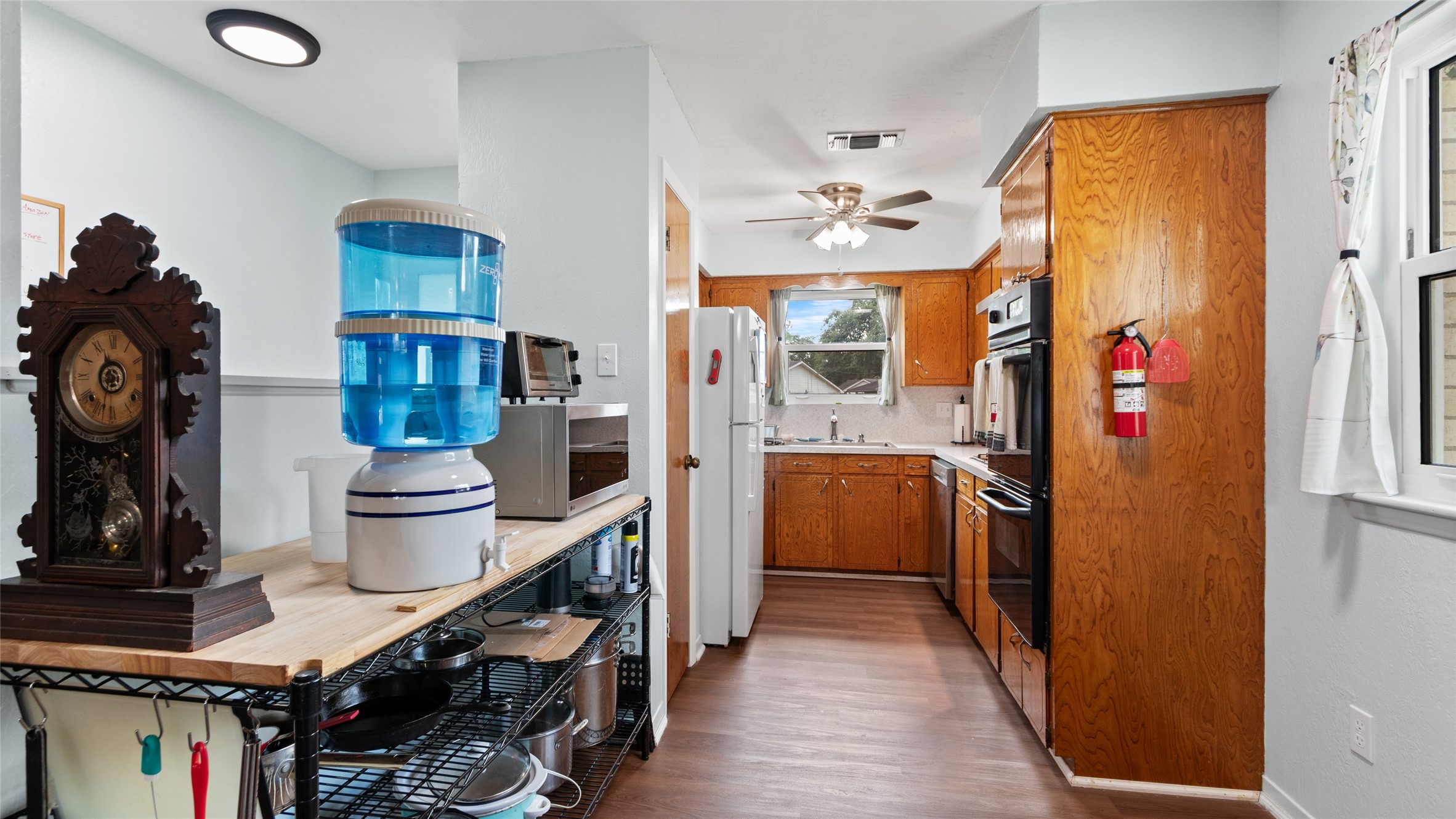 Galley-style kitchen offers abundant cabinetry, generous workspace, wood-look flooring, and multiple windows providing natural light.