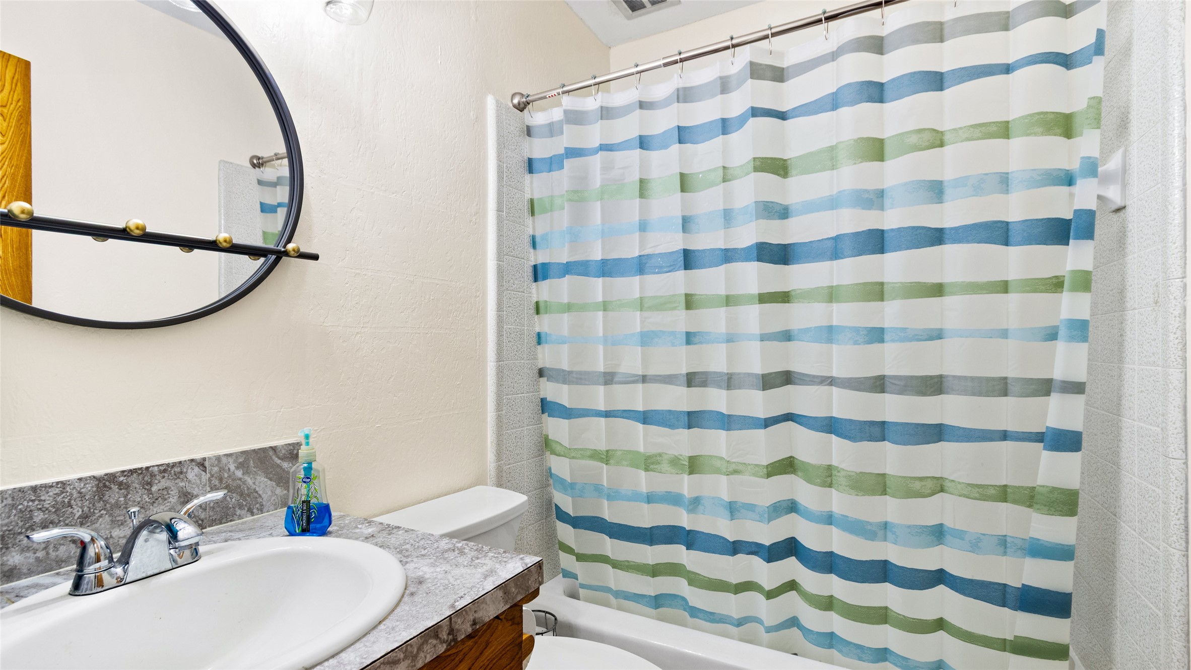 Secondary full bathroom features a tub/shower combination with tiled surround, generous vanity counter space, and a clean, functional layout.