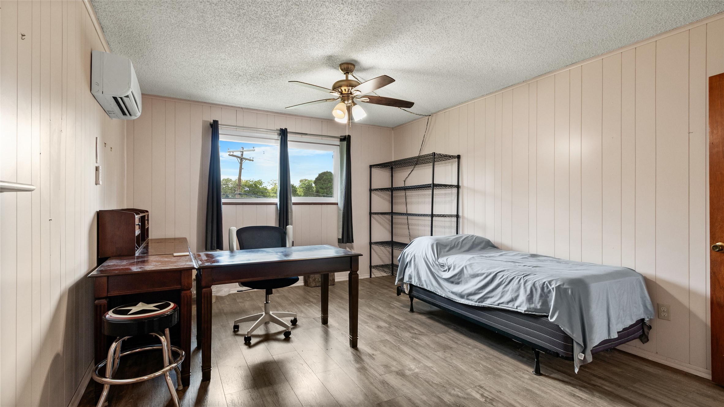 Generously sized secondary bedroom offers abundant natural light, wood-look flooring, a ceiling fan, and plenty of flexibility for a bedroom, home office, or multipurpose space.