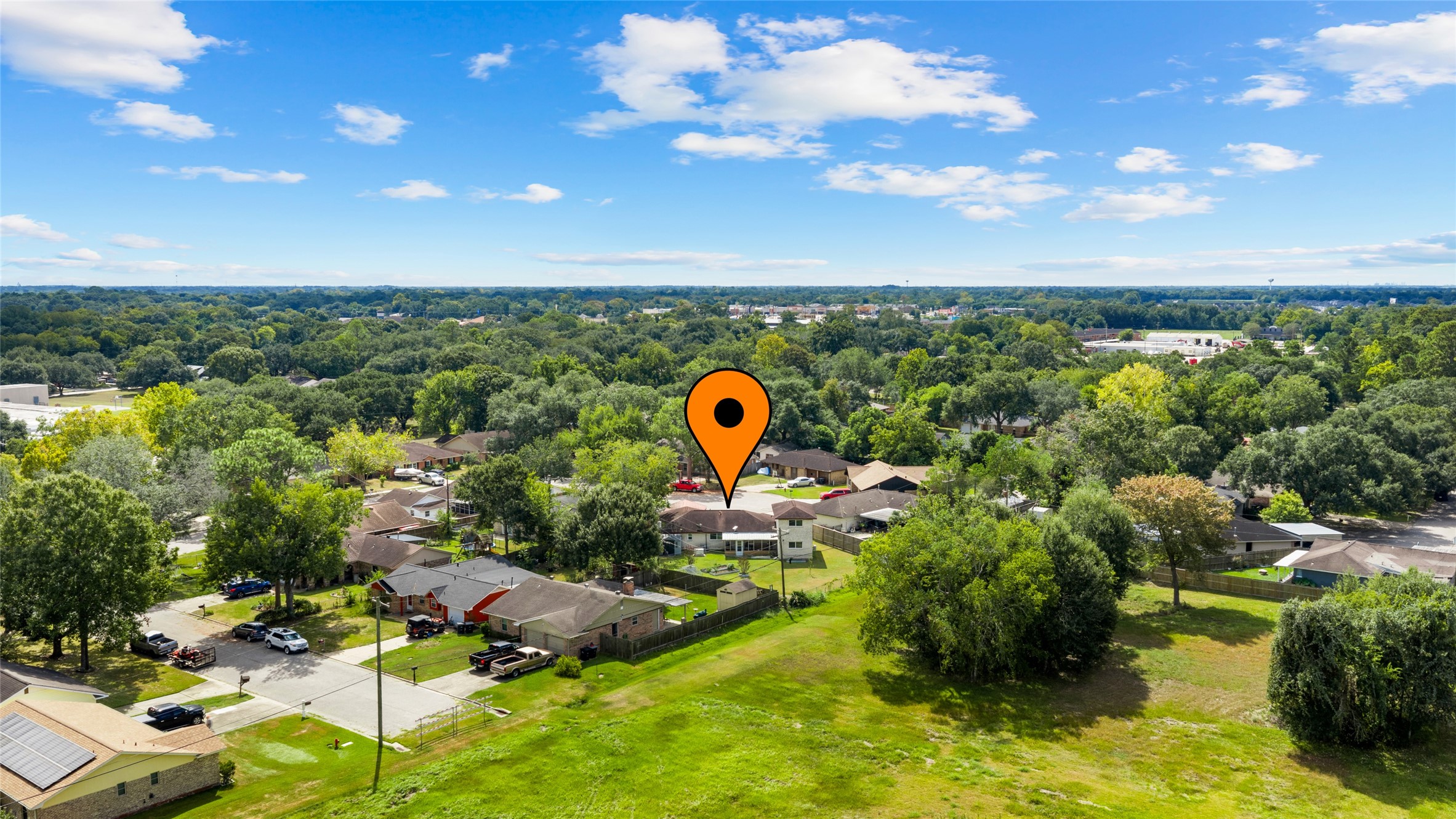 Aerial view highlights the homes location within an established residential neighborhood, surrounded by mature trees and nearby green space.