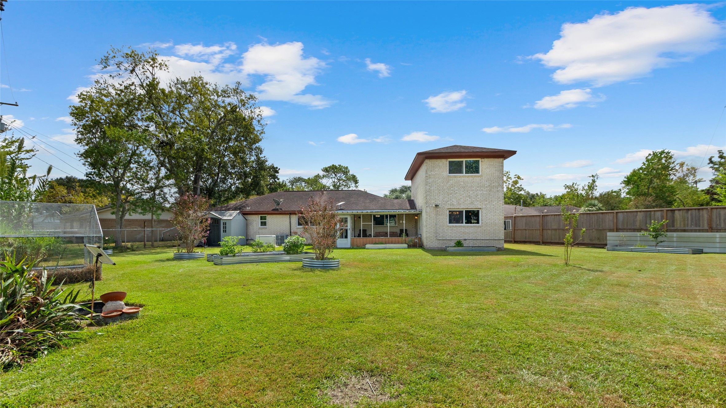 Wide backyard view highlights the homes generous outdoor space, raised garden beds, greenhouse, and screened-in patioplenty of room to garden, entertain, play, or simply enjoy the outdoors.