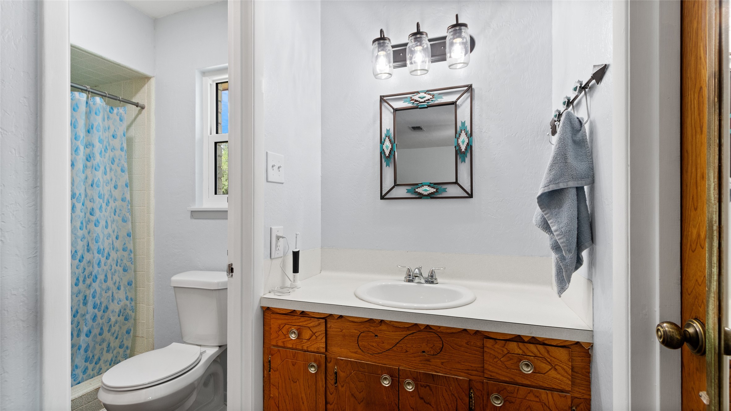 Full bathroom features a generous vanity with ample counter space, tub/shower combination, and a window providing natural light.