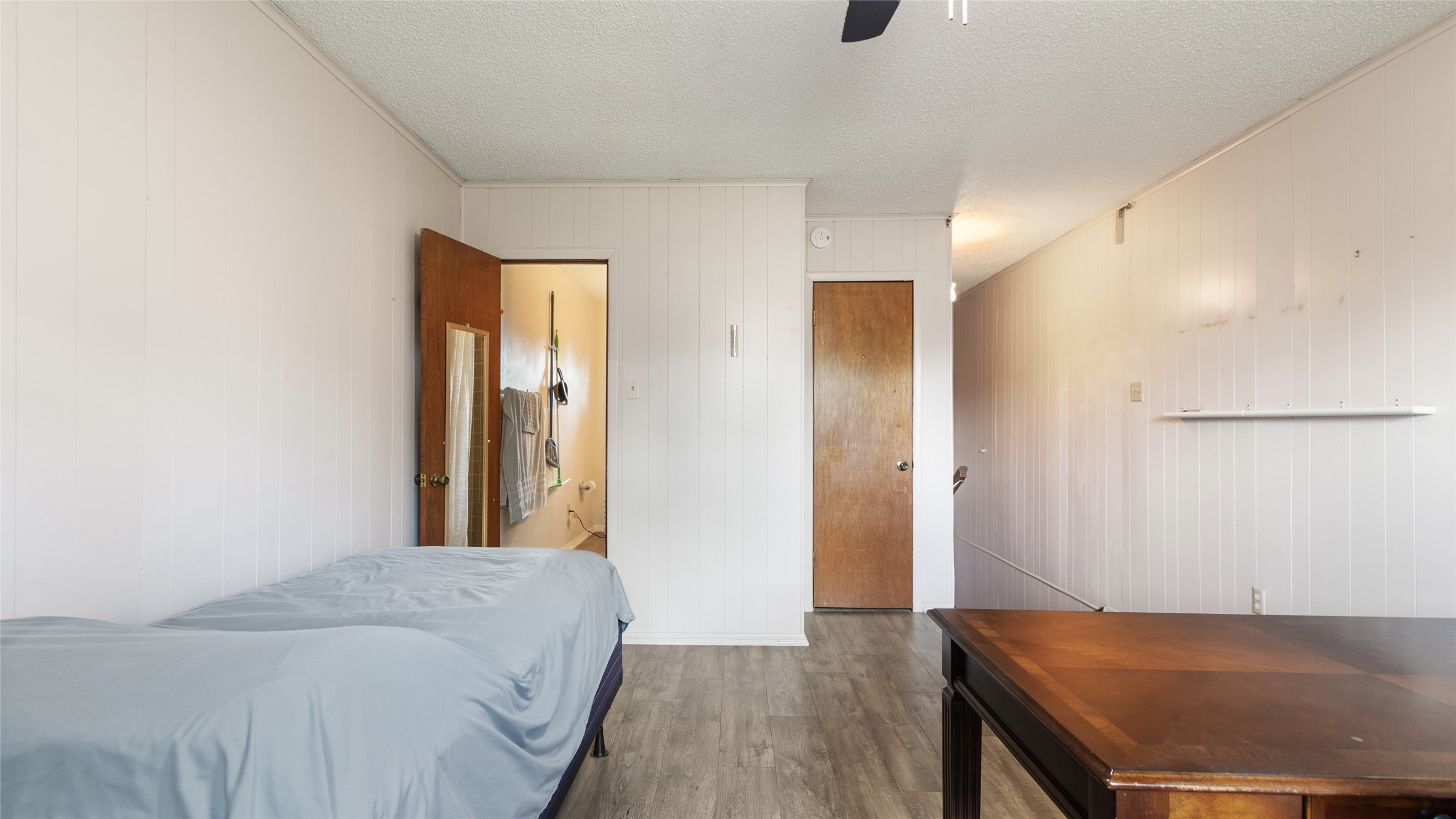 Another view of the generously sized secondary bedroom, highlighting the flexible layout, wood-look flooring, and convenient access to the adjoining bathroom.