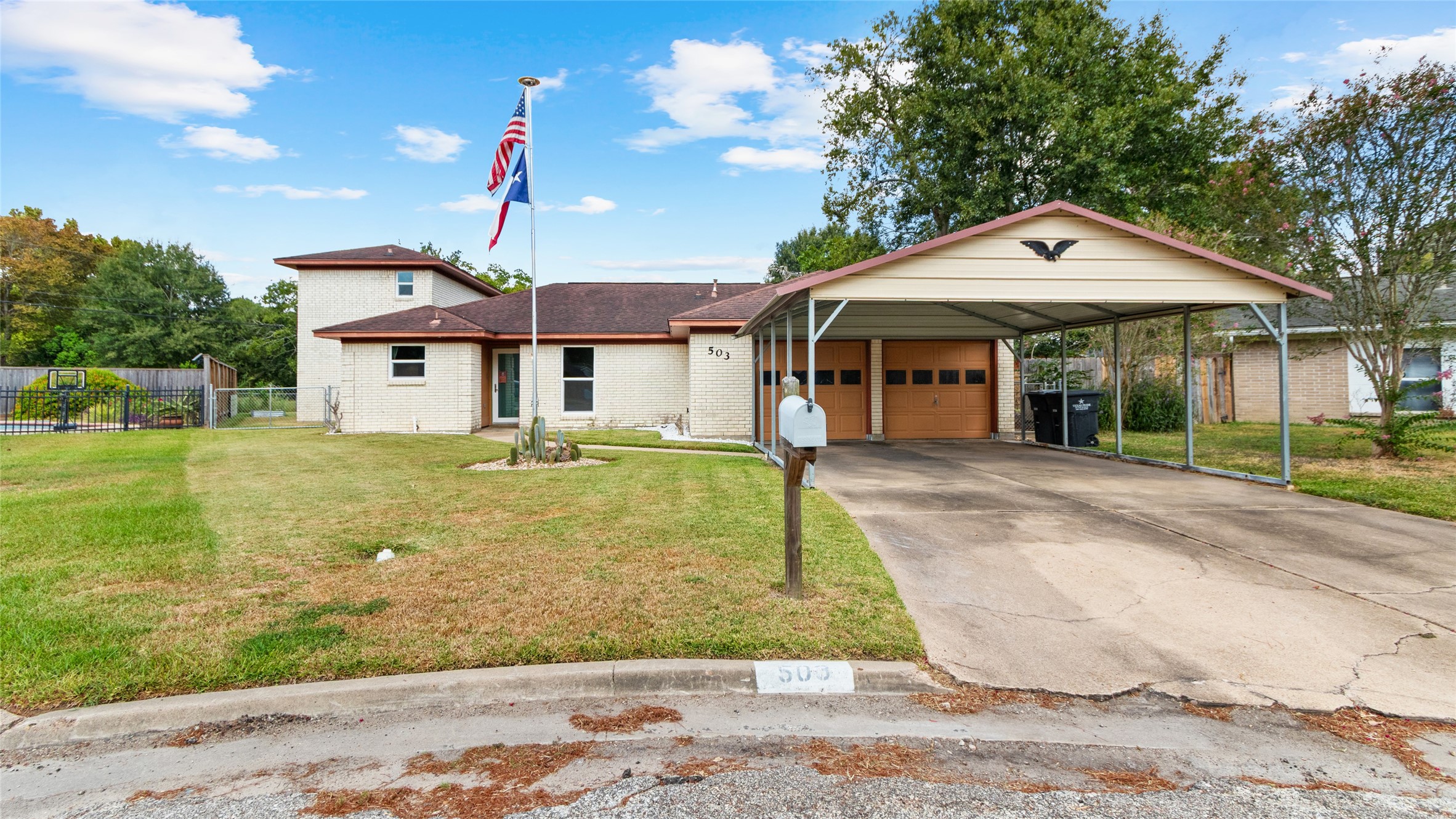Front exterior view showcases the homes distinctive multi-level design, attached garage, and extended covered carport providing ample off-street parking.