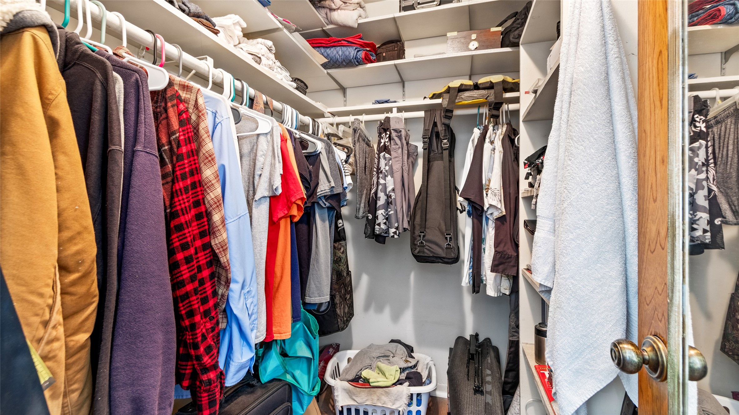 Generous walk-in closet offers abundant hanging space and built-in shelving for organized storage.