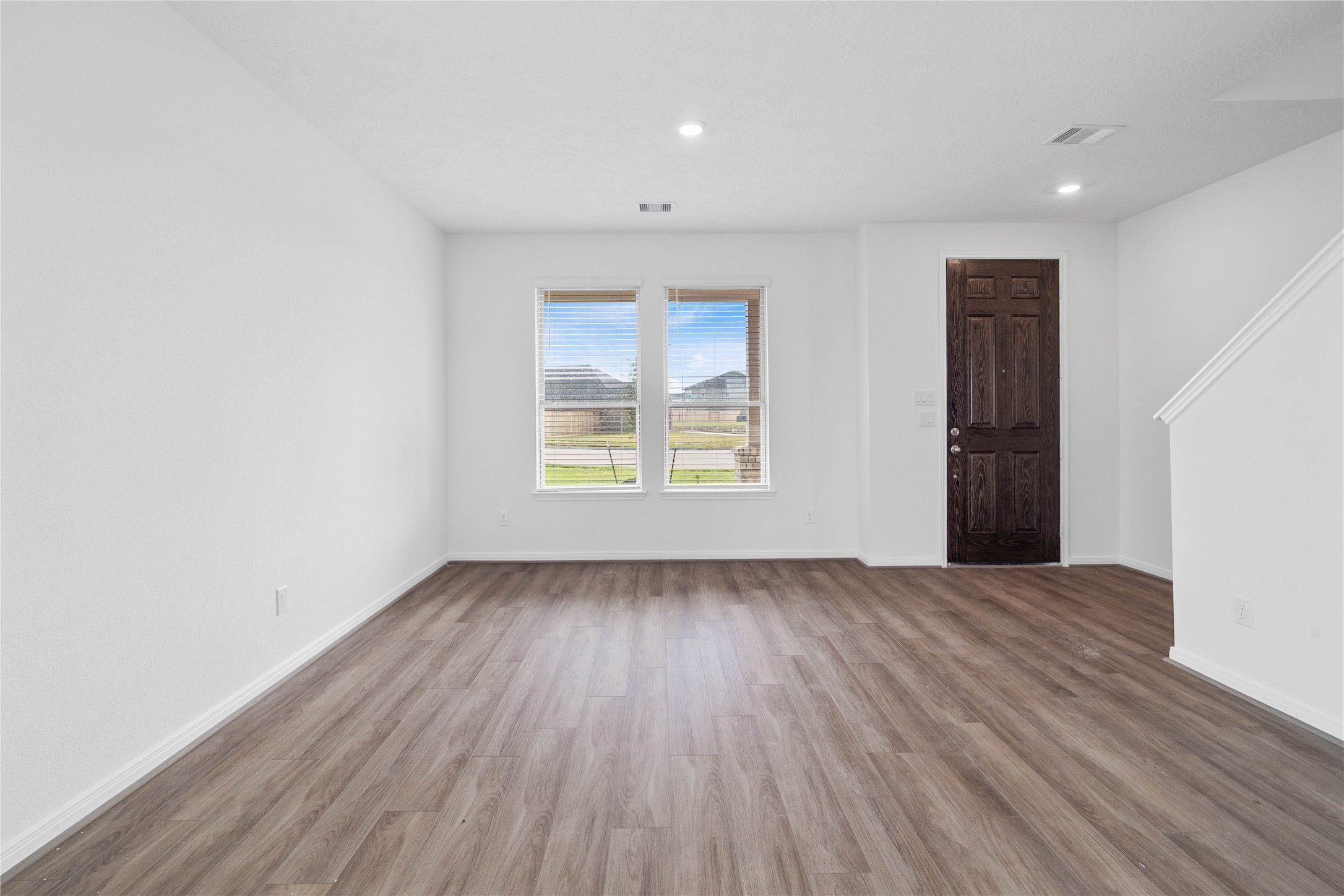 The formal living room offers a polished, elegant space designed for entertaining guests and special occasions. Featuring the gorgeous vinyl plank flooring, neutral paint, high ceilings, recessed lighting, and large windows with privacy blinds.