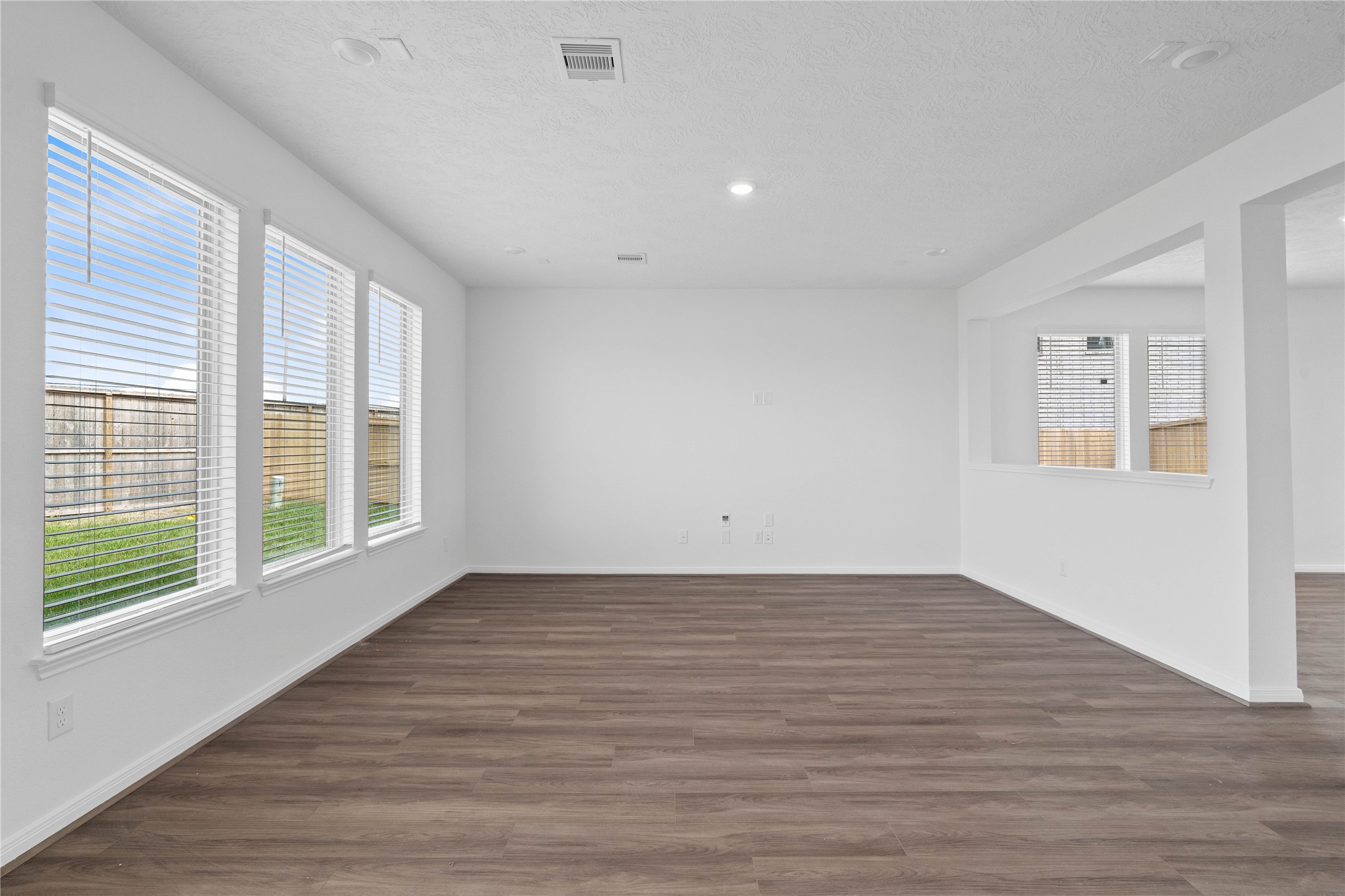 Bring family and friends together in this beautiful family room! It features high ceilings, recessed lighting, custom paint, stunning flooring, and large windows that fill the space with natural light all day long.