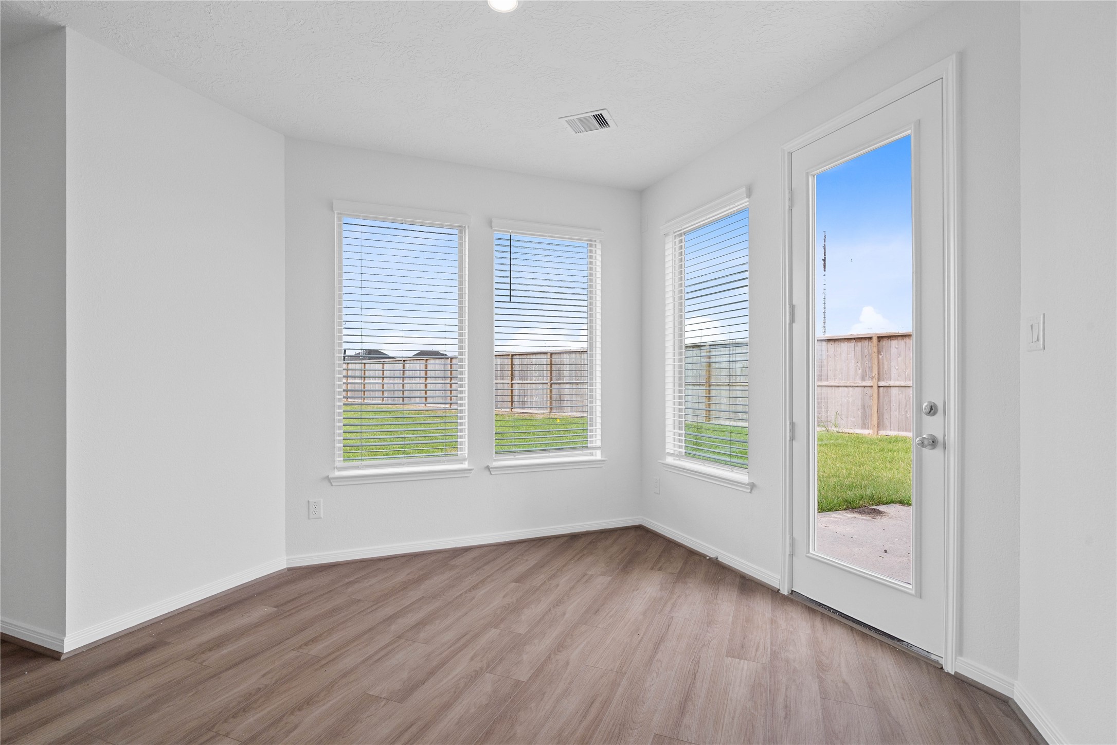 Start your day with a warm cup of coffee and quality time in this charming breakfast nook! Highlights include large windows with blinds, custom neutral paint, vinyl plank flooring, recessed lighting, high ceilings, and a convenient door leading to the rear patio slab and backyard.