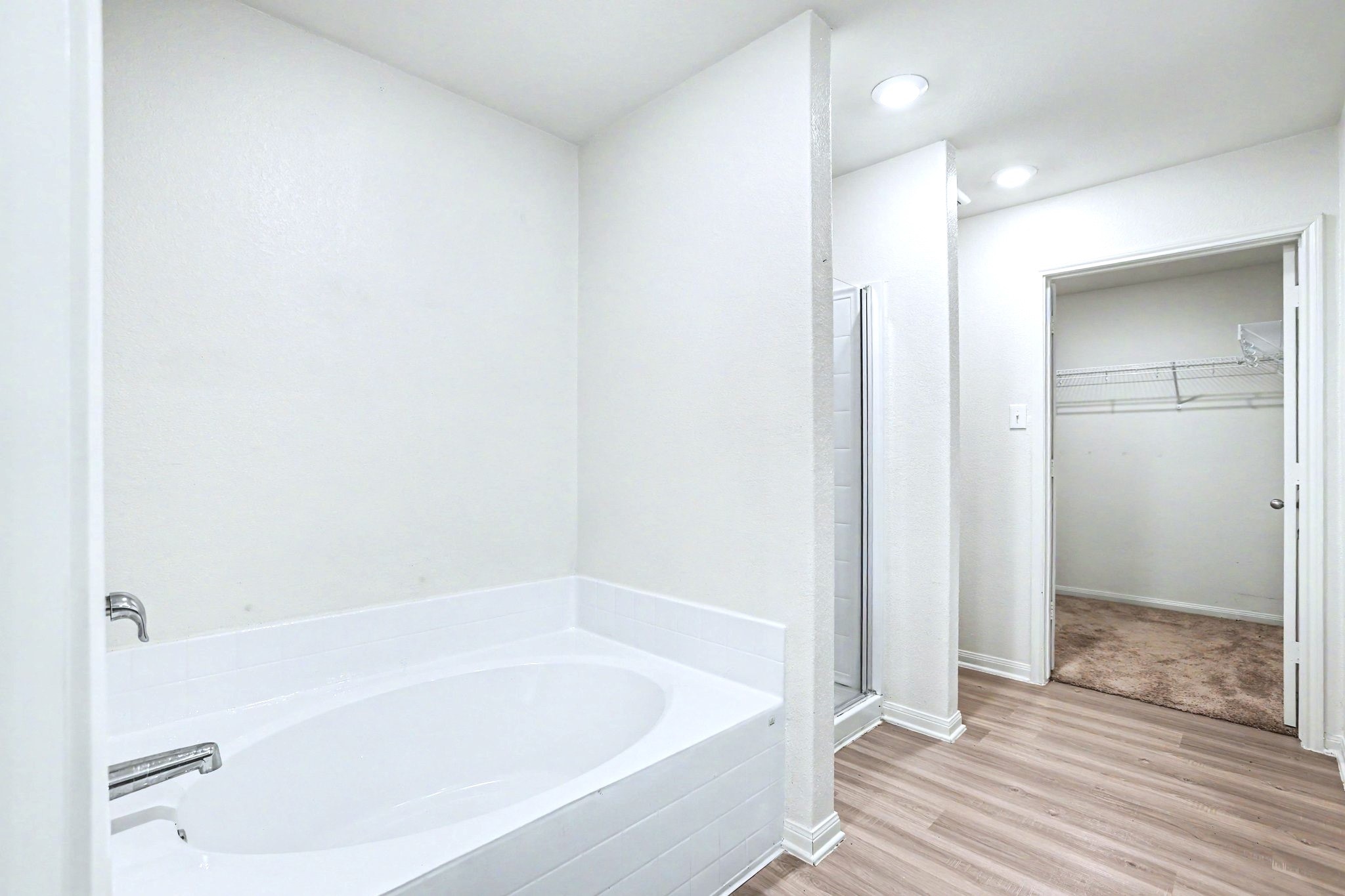 Another view of the primary bath including soaking tub, separate shower and large walk-in closet