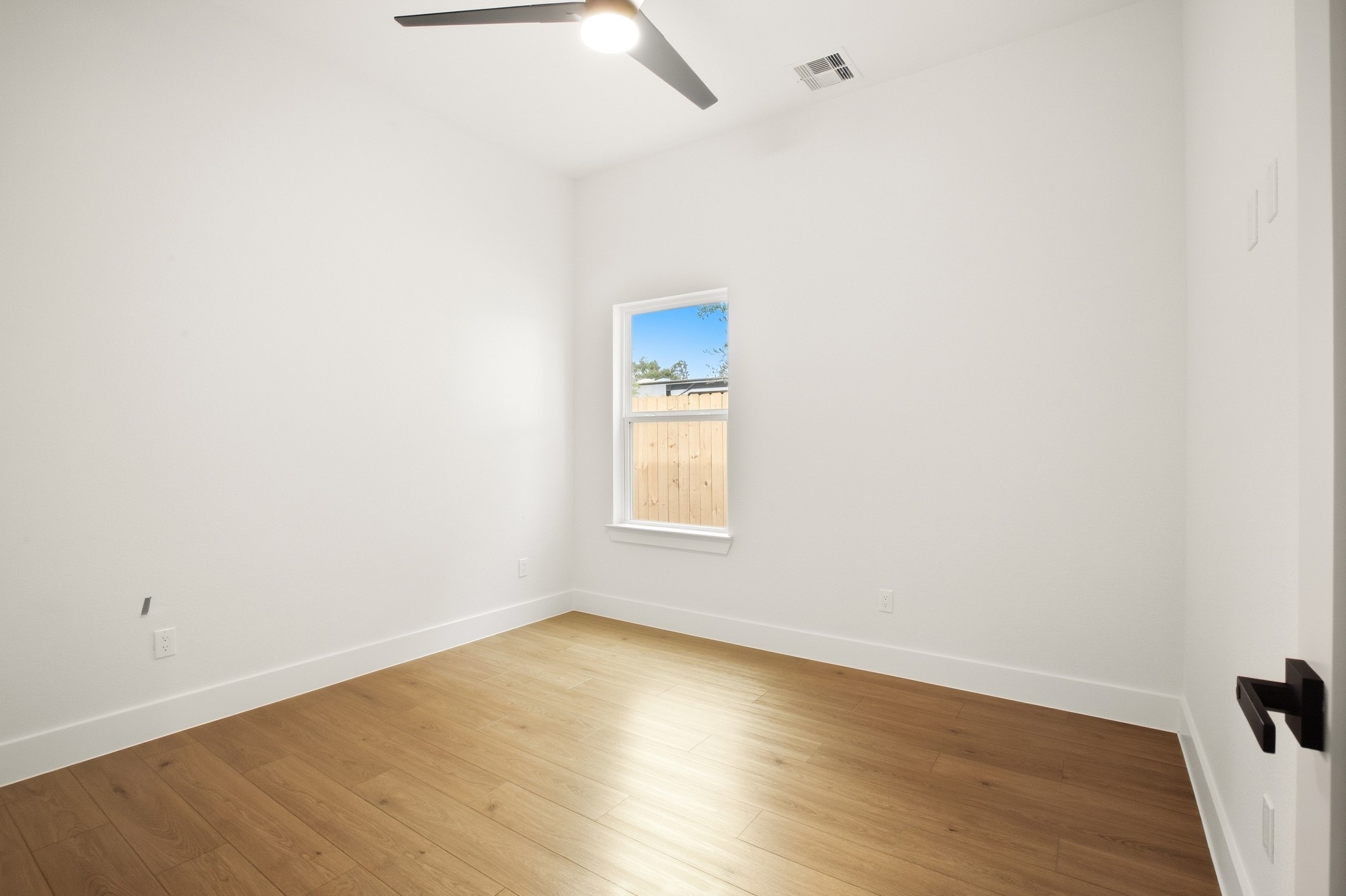Comfortable bedroom with natural light and warm wood flooring.